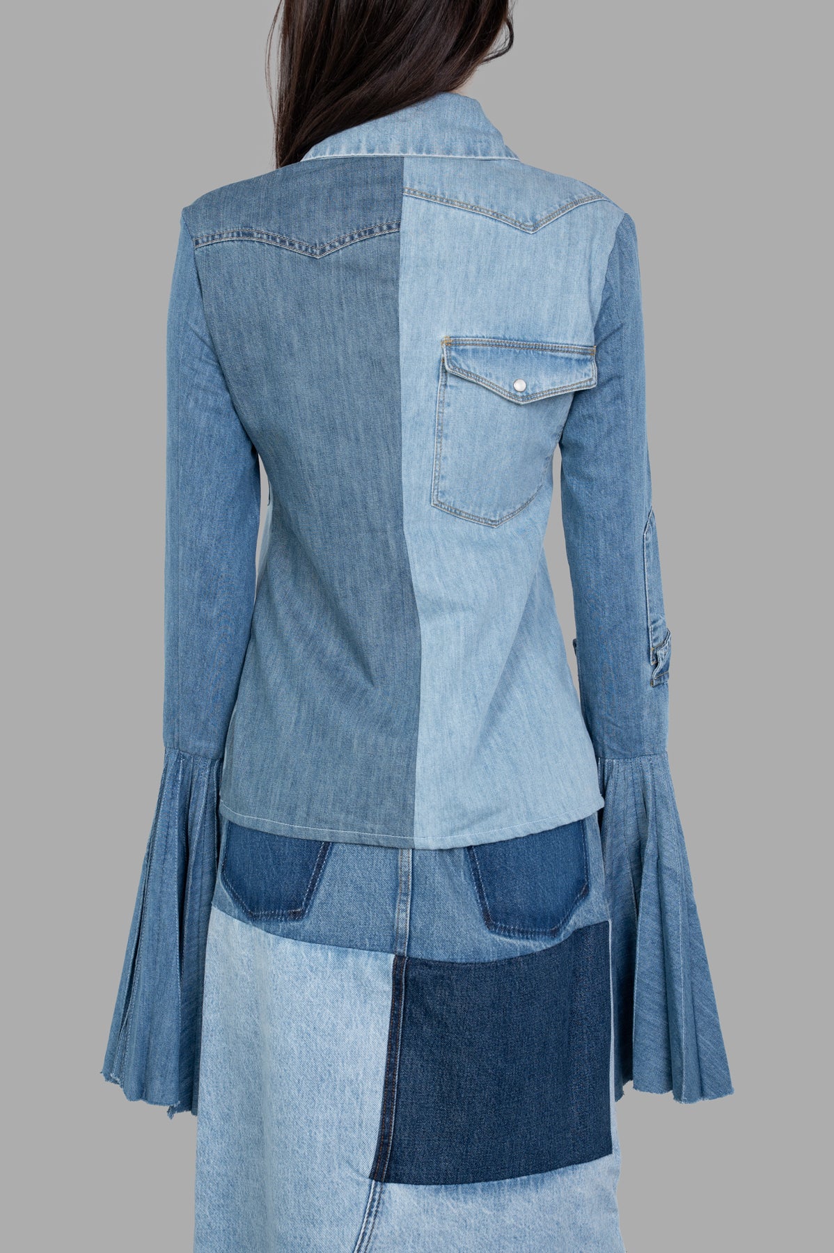 A.W.A.K.E. MODE Denim Shirt With Pleated Sleeves, showcasing a side view with unique patchwork and flared cuffs on a model.