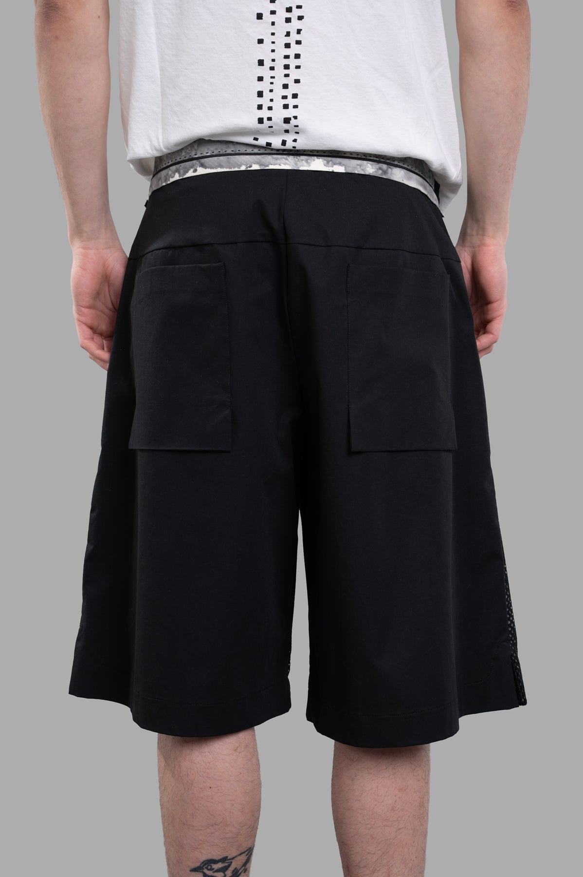 Giovanni Cavagna Perforated Shorts in black, highlighting the detailed perforations and relaxed silhouette from a side angle.