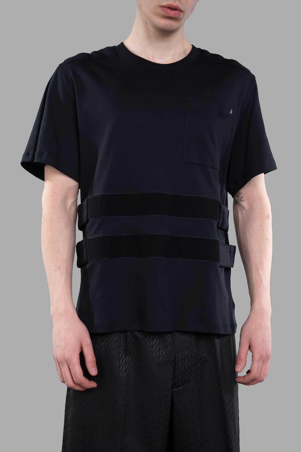 Helmut Lang Armor T-shirt on model, featuring a front view with straps and a pocket detail. Stylish and modern design.