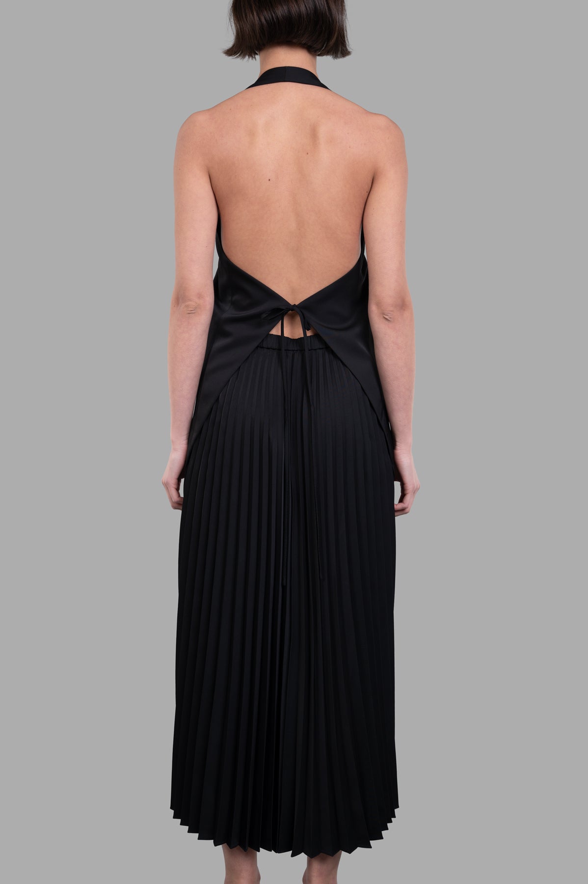 Helmut Lang Halter Vest Dress, showcasing the back with pleated skirt and tie detail, crafted in fluid black twill.