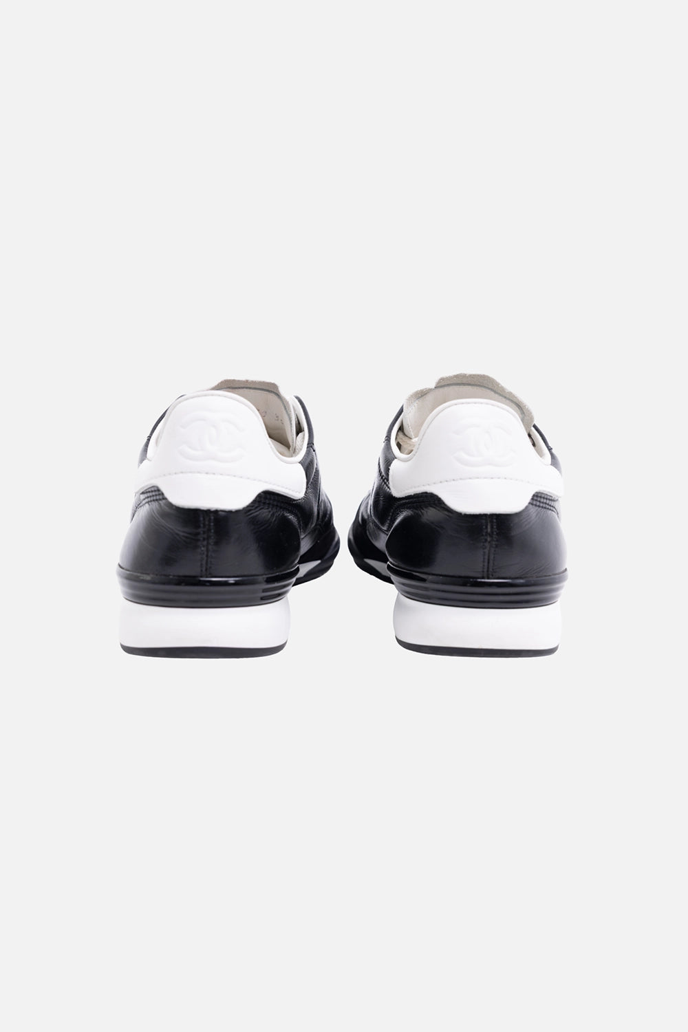 Pre-owned Chanel women’s low-top sneakers in black and white, back view, white heel tabs with embossed CC