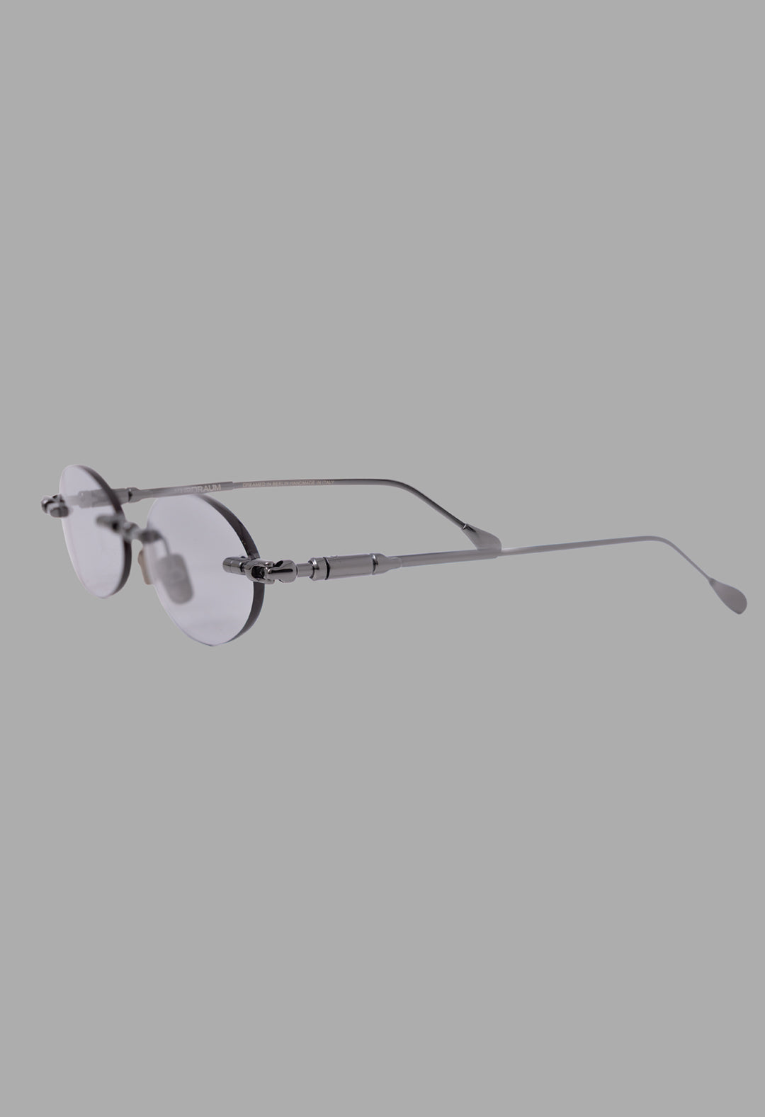 Kuboraum unisex rimless sunglasses in gunmetal grey, three-quarter view showing tubular temples and linked metal bridge.