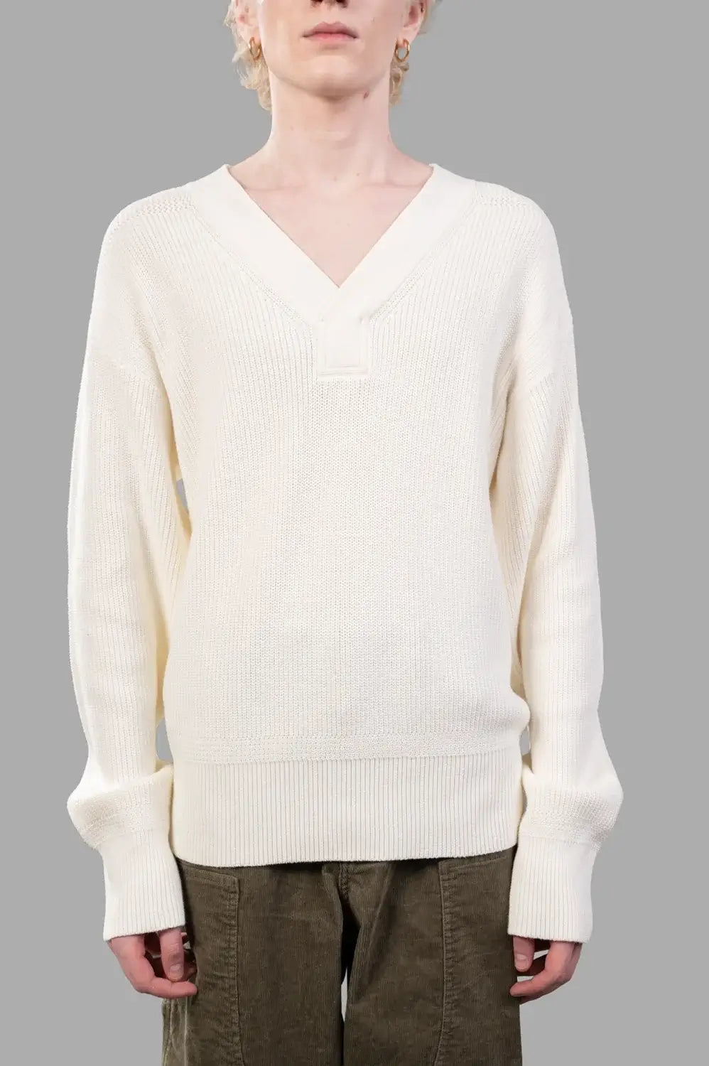 Front close-up of white ribbed V-neck sweater showing wide rib knit and V overlay