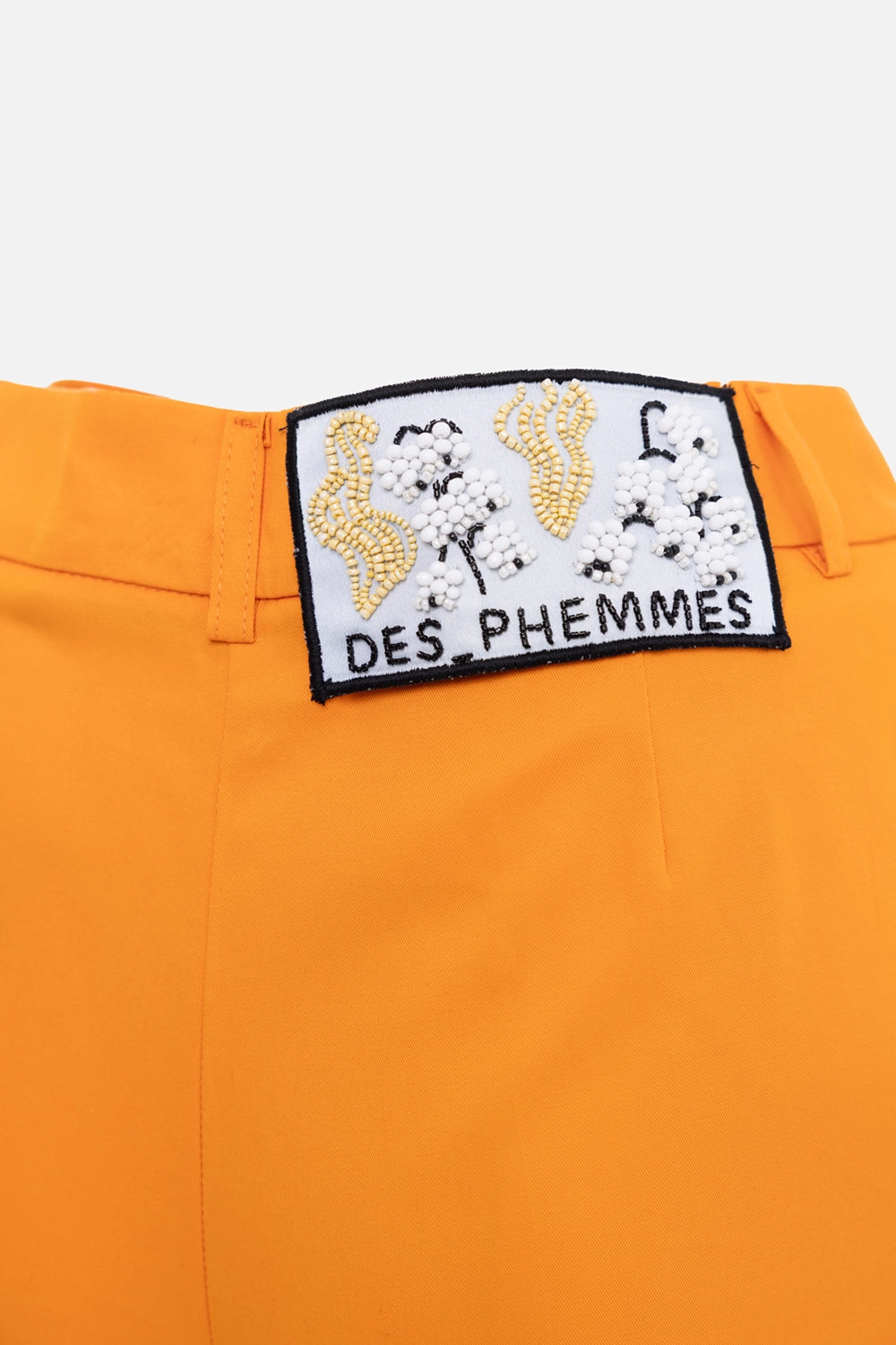 Des Phemmes women's capri pants in tangerine, logo detail view, beaded back patch on waistband