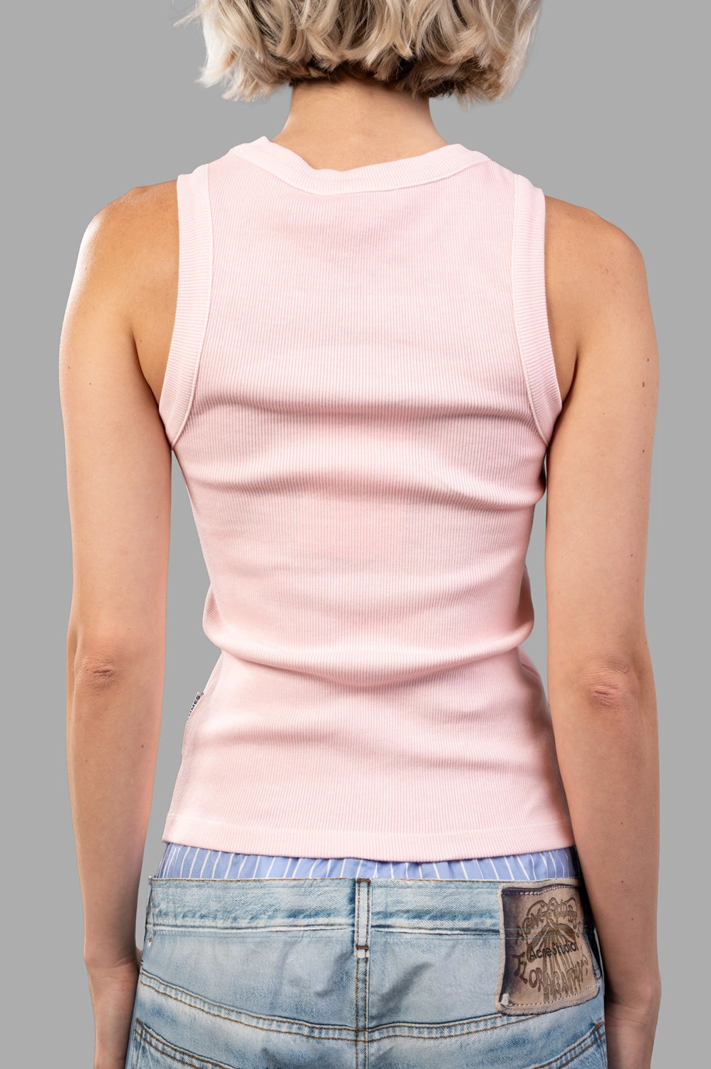 Back view of light pink ribbed tank showing clean finish and close fit
