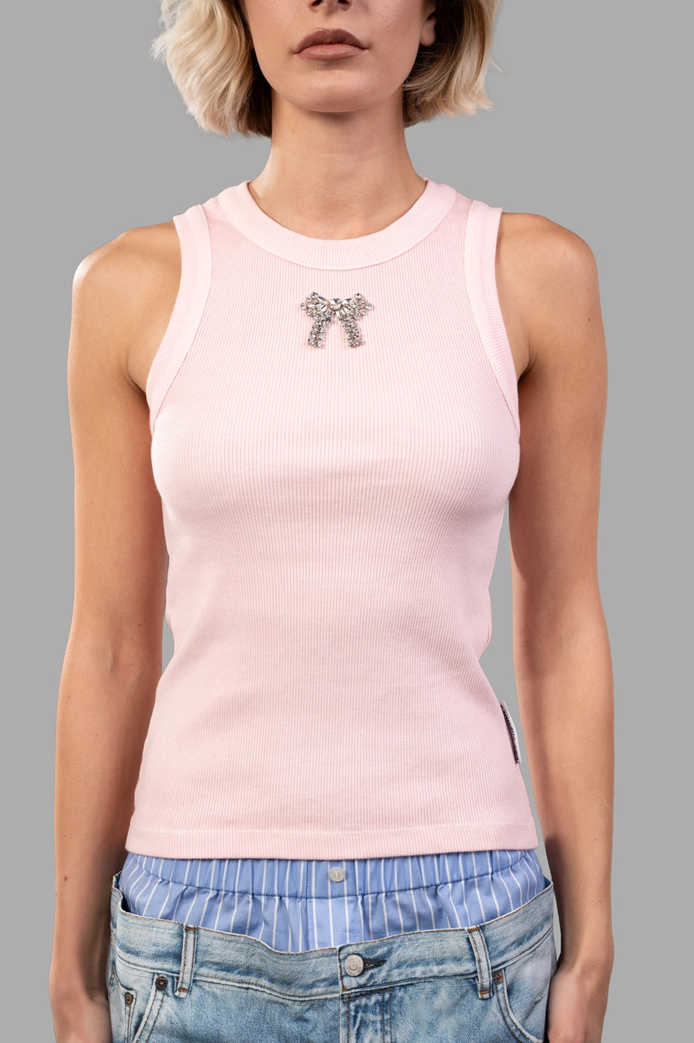 Front close-up of light pink ribbed tank; crystal bow at chest, wide neck and arm bindings