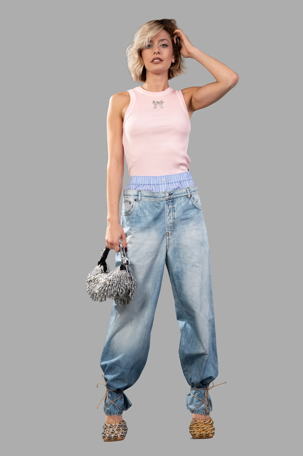 Full-length view of a light pink ribbed tank top with crystal bow accent, fitted cut