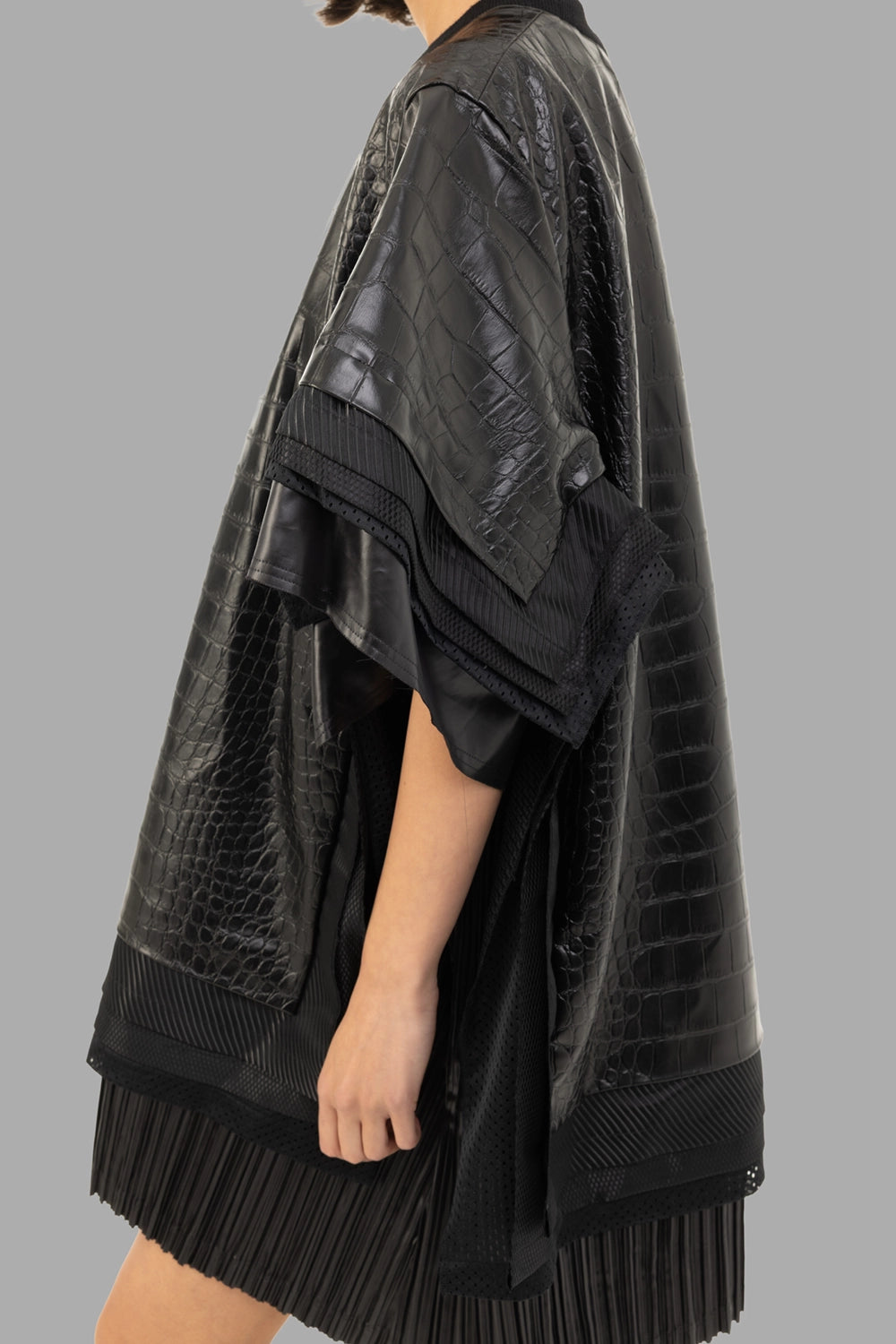 Junya Watanabe women’s faux-leather top in black, side view, layered sleeve trims and mesh panel