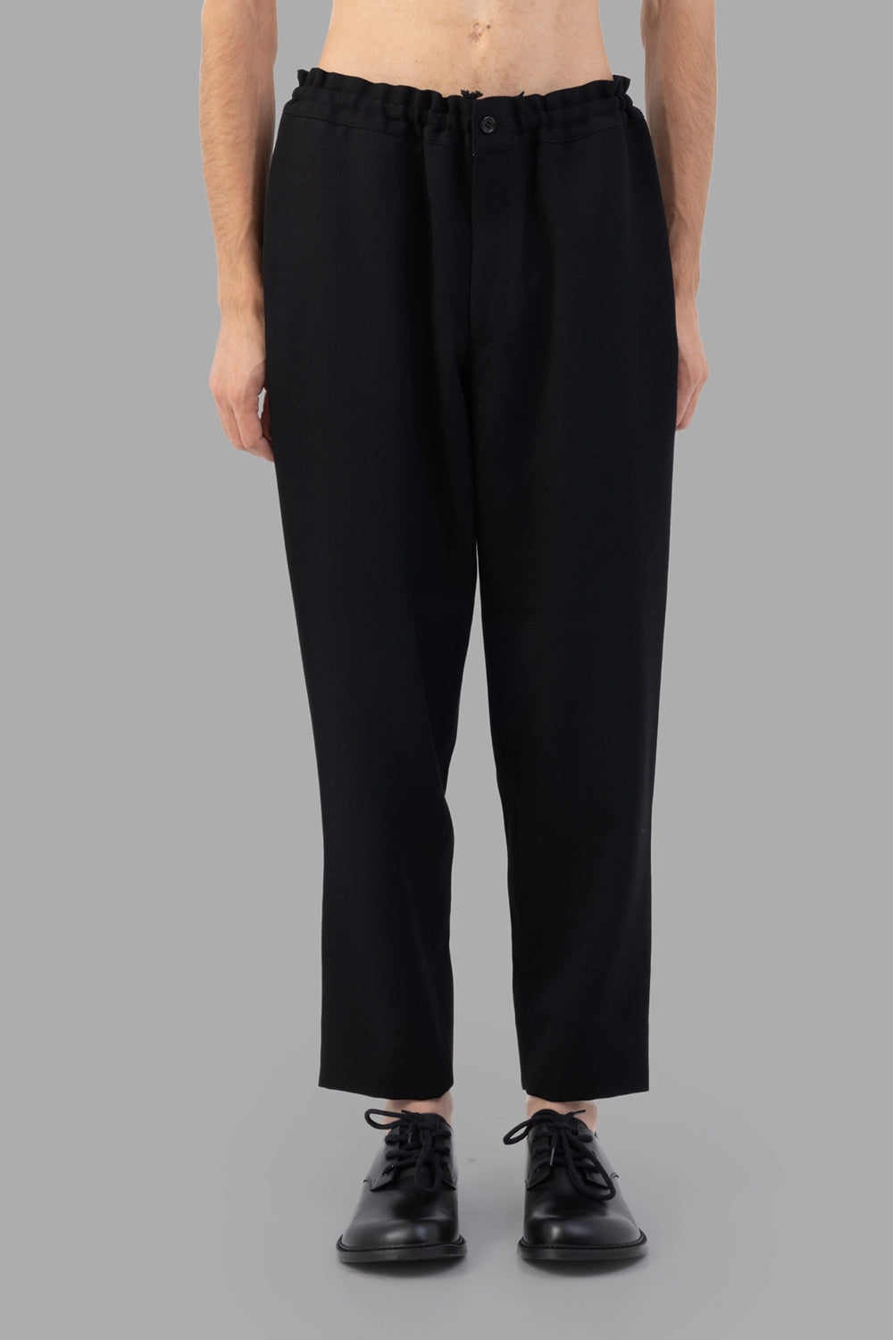 Comme des Garçons trousers in black, front view, elastic waistband with button closure