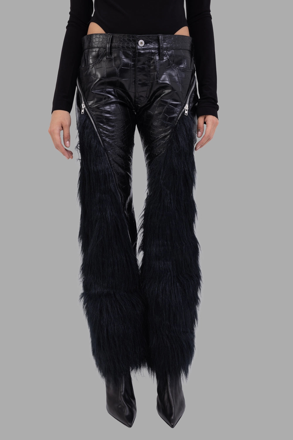 Junya Watanabe women faux-leather trousers in black, front view, diagonal metal zips and five-pocket waist.