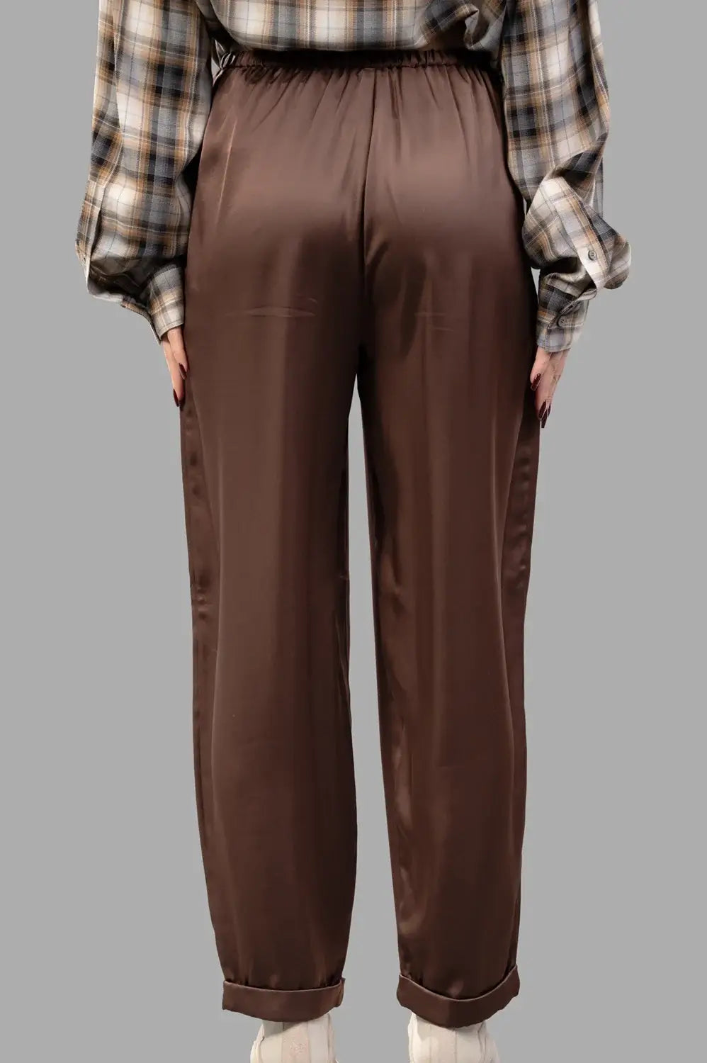 Back close-up of brown satin trousers showing elastic back waist and cuffed hem