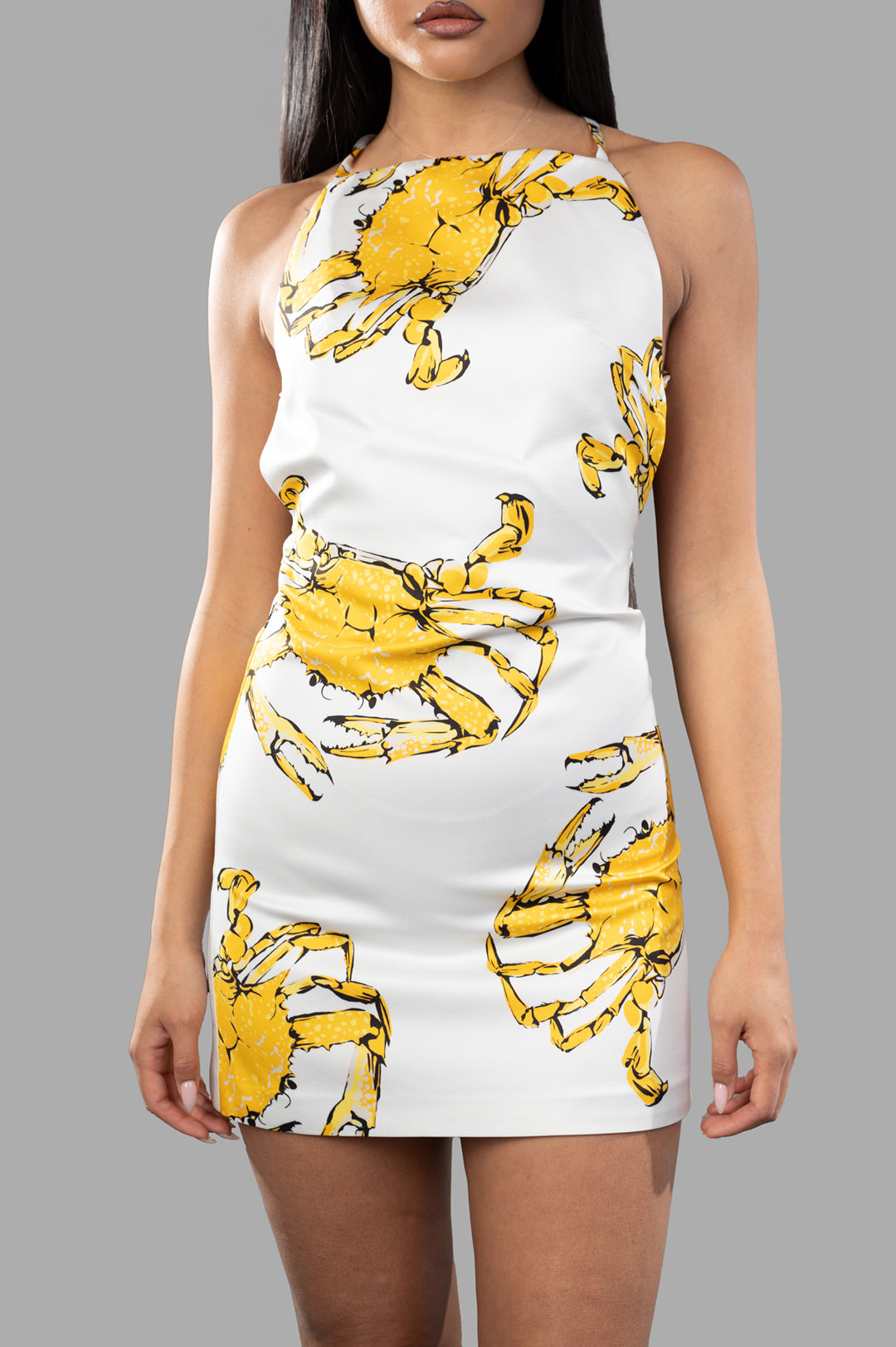 **MSGM Crab-print Dress featuring bold yellow crab graphics, square halterneck, and criss-cross open back, modeled in white.**