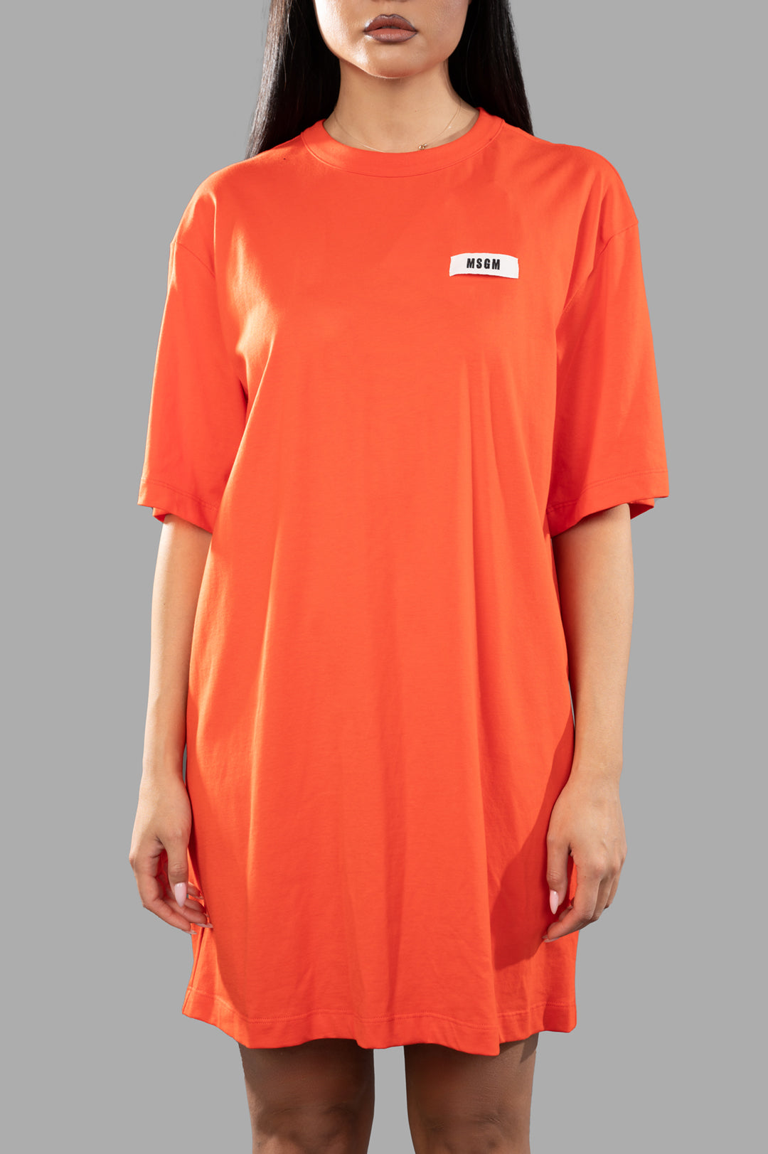 MSGM Orange T-shirt Dress featuring a branded logo on side, showcasing a relaxed fit and soft cotton material on model.