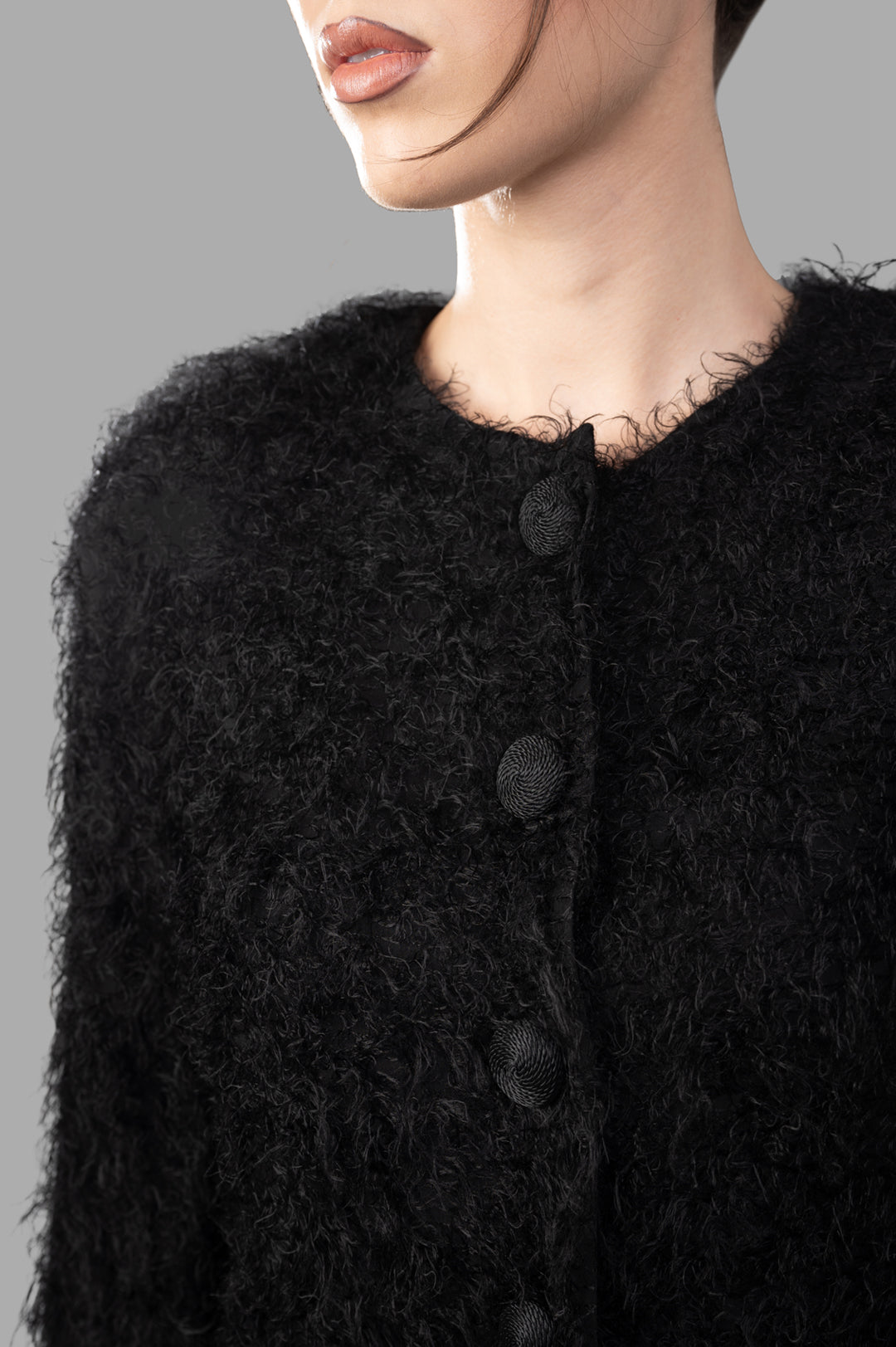 By Malene Birger Stephania Cardigan in black, captured from the side, highlighting its plush fabric and round neckline.