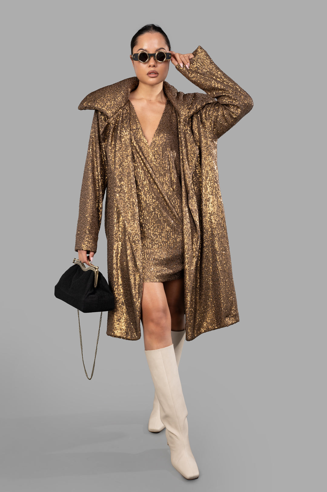 Norma Kamali Sequin Trench in bronze, front view on model wearing sunglasses, showcasing wide lapel and knee-length design.