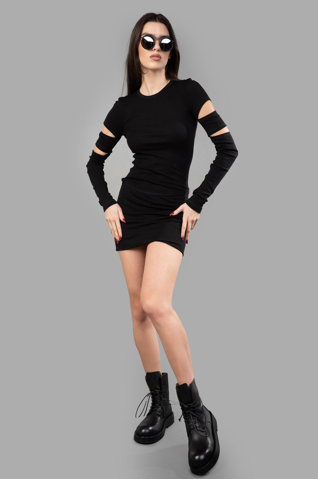 Helmut Lang Slash Mini Dress in black with cut-out sleeves, front view on model, styled with sunglasses and boots.