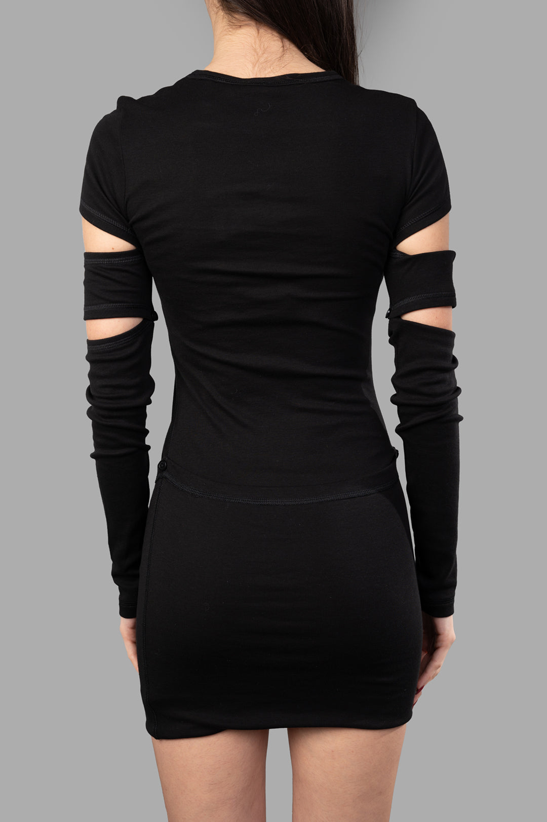 Helmut Lang. Black Slash Mini Dress featuring cut-out detailing and detachable sleeves, shown from the back on a model.
