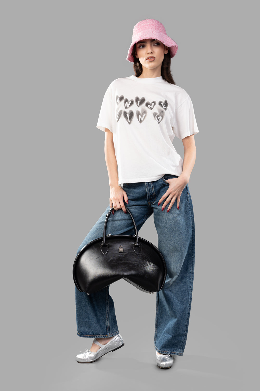 Anine Bing Spencer Hearts T-shirt on model, featuring heart logo, relaxed fit, styled with jeans and a pink hat.