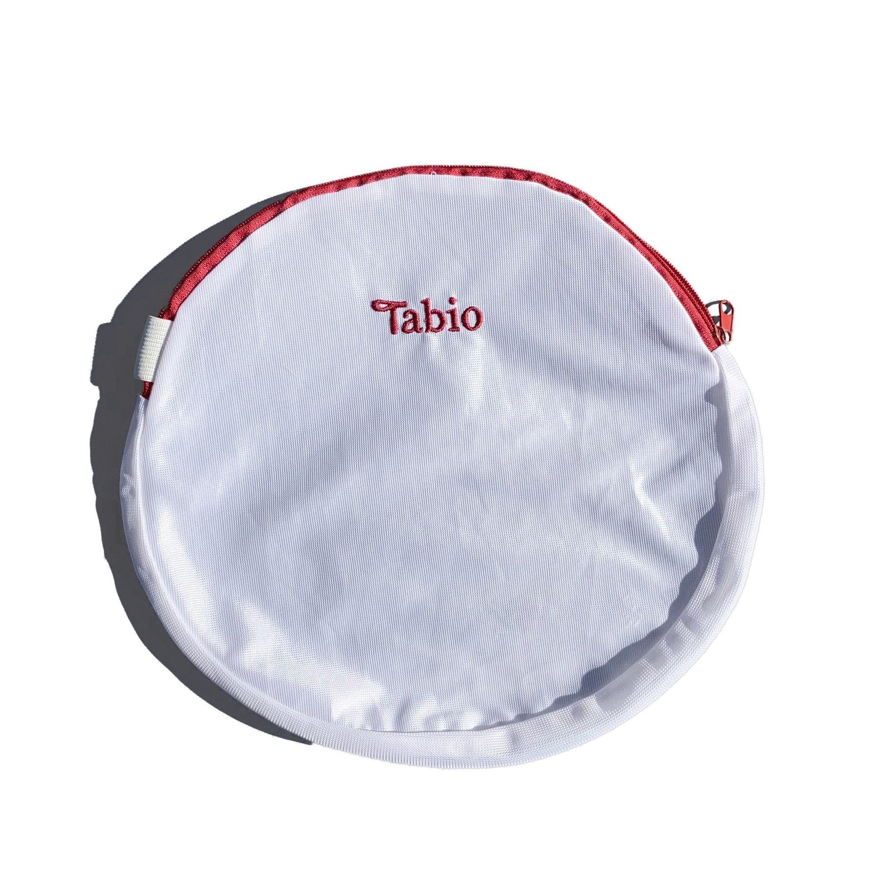 Tabio Sock Washing Net in white, round with red zipper, front view. Protect delicate socks in wash. Polyester material.