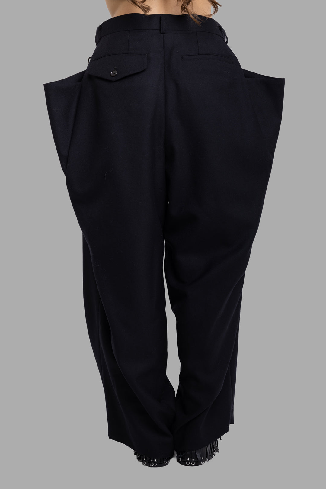 Noir Kei Ninomiya black wool trousers, back view with tailored seat, flap pockets and structured side volume