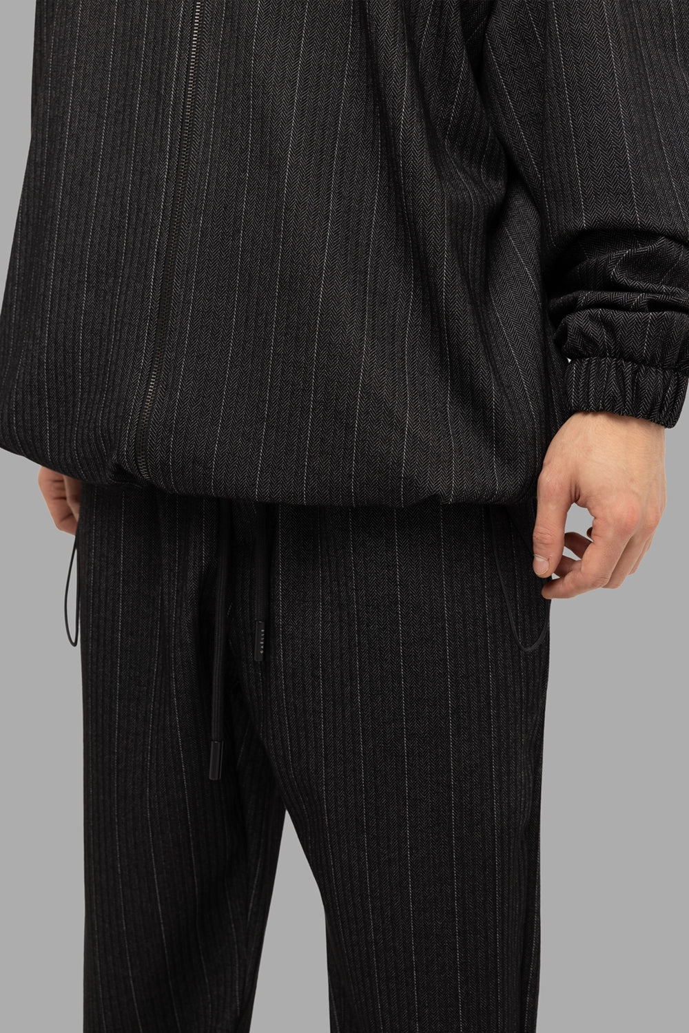 Gaëlle Paris men’s zip jacket in black, hem detail, herringbone pinstripe knit and elastic cuff.