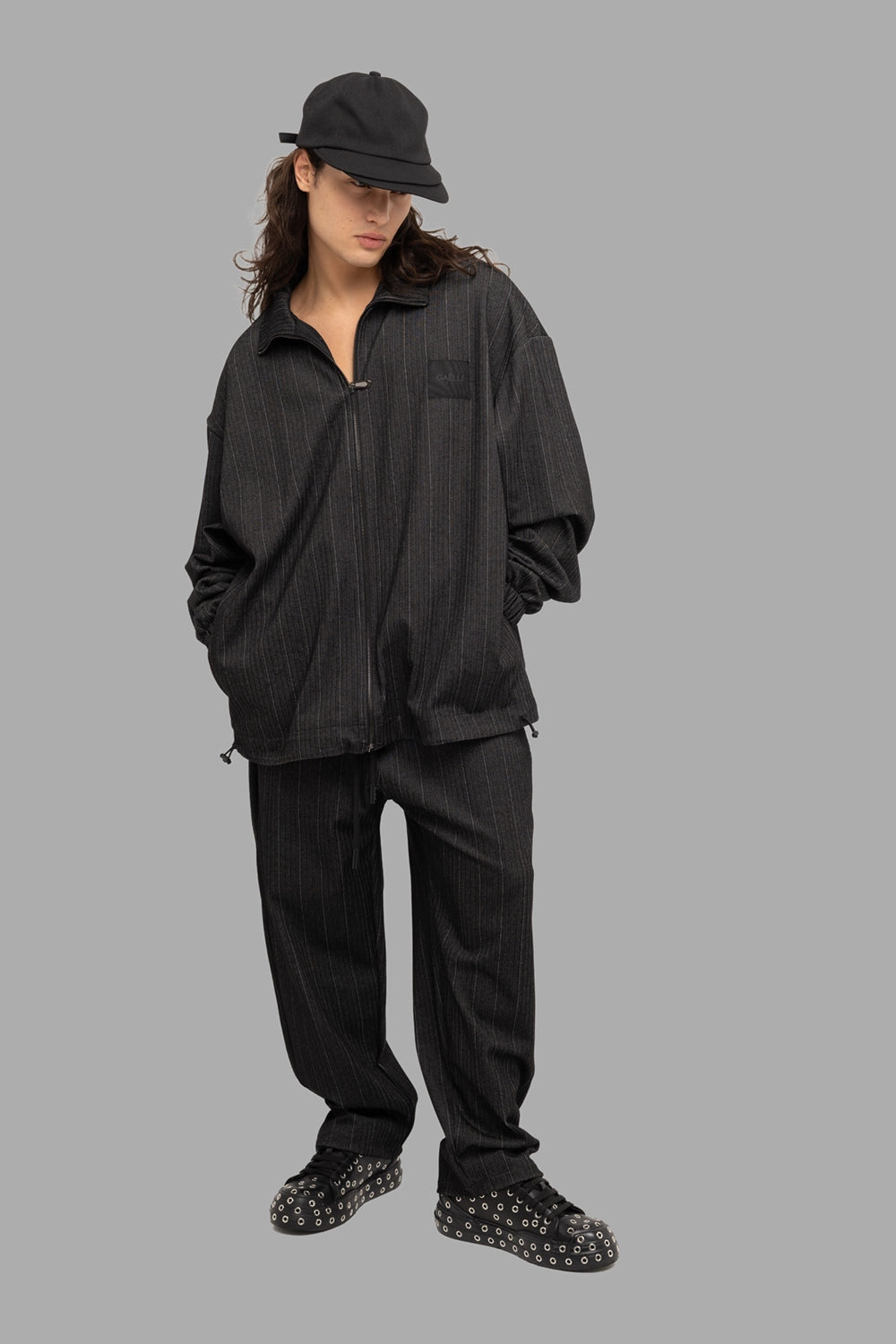 Gaëlle Paris men’s zip jacket in black, on-model full length, relaxed fit and pinstripe herringbone knit.