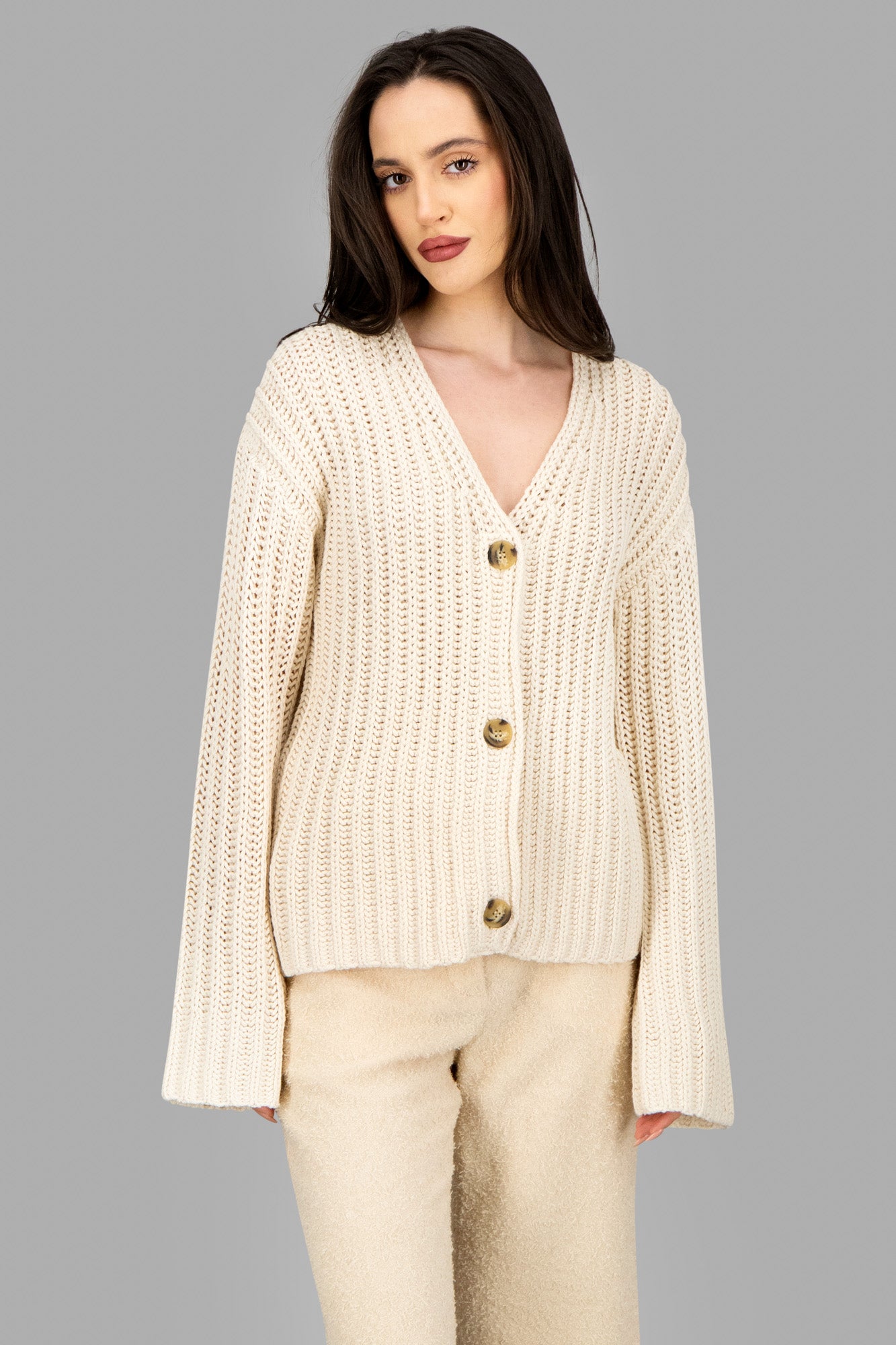 By Malene Birger Cable-Knit Cardigan displayed on model, featuring a deep V-neck and double-breasted buttons in soft beige.