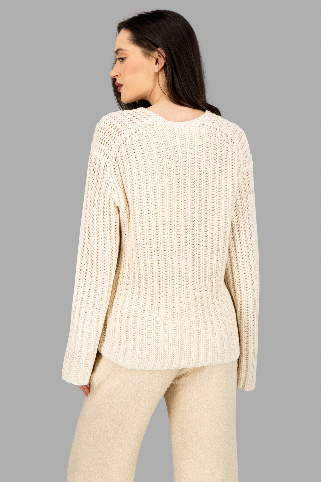 By Malene Birger Cable-Knit Cardigan shown from the back on a model, featuring a textured, cozy design in cream.