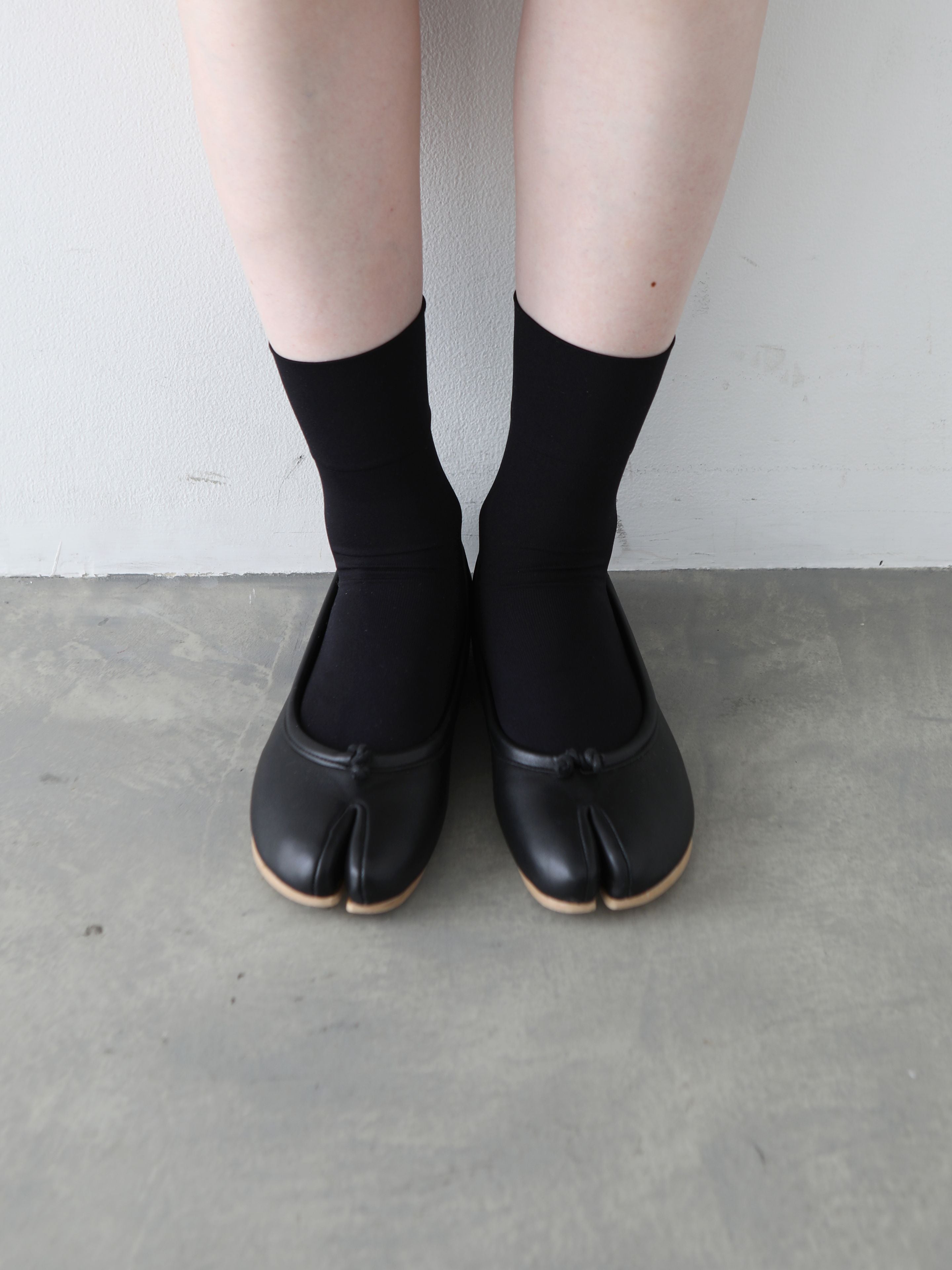 Tabio Soft Nylon Low Crew Tabi Socks in black, worn with tabi shoes, showcasing soft, stretchy material and unique design.