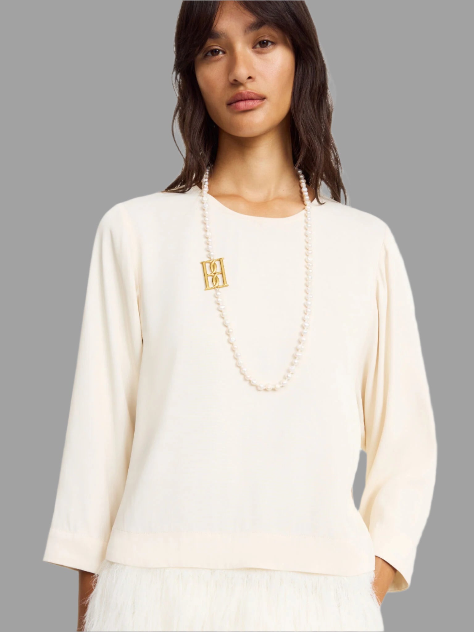 By Malene Birger. Chakallo Monogram Necklace featuring natural pearls and a bold golden monogram, styled on a model.