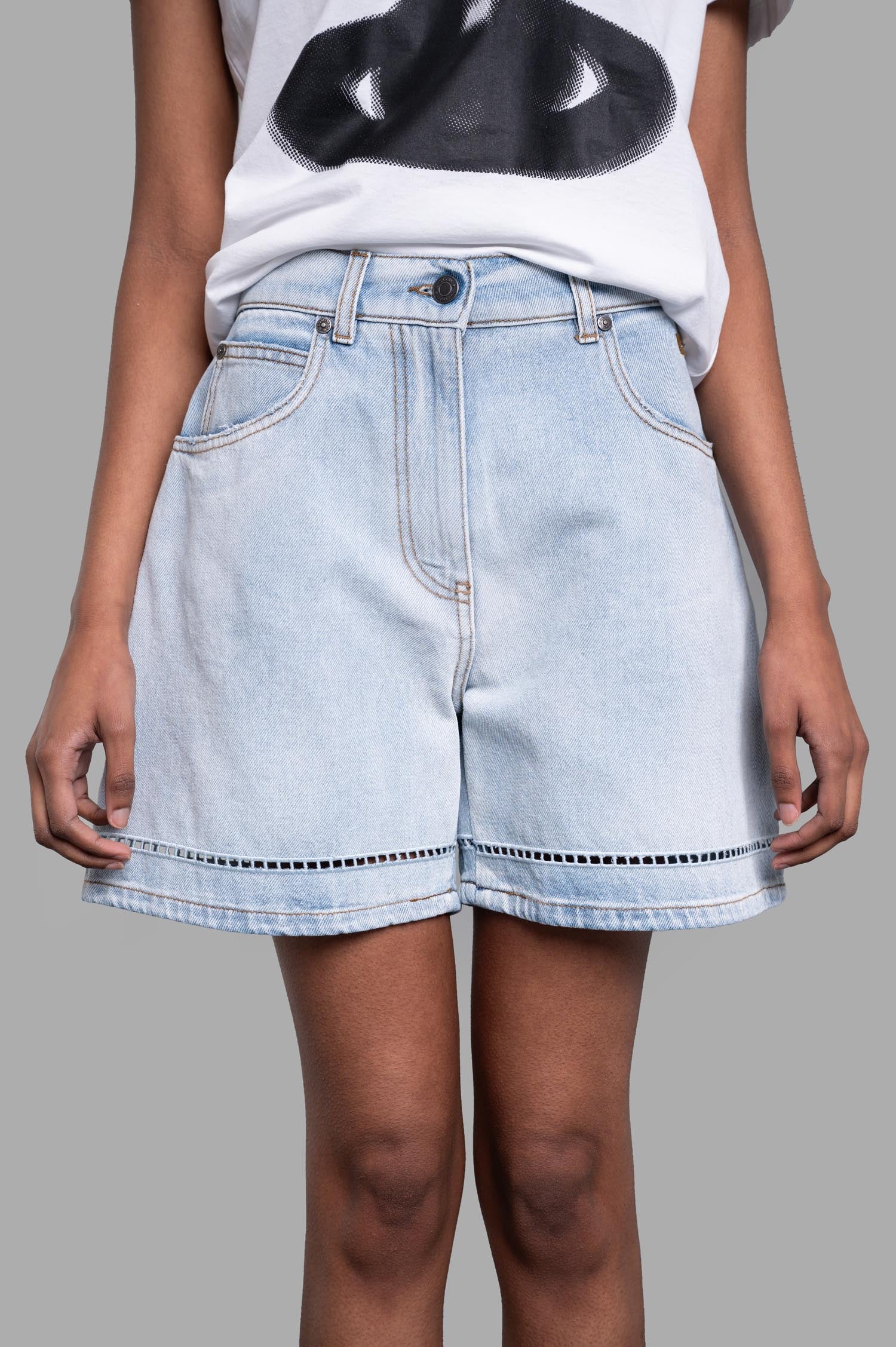 MSGM light blue denim shorts highlighted by broderie anglaise trim and contrasting stitches, displayed from the side.