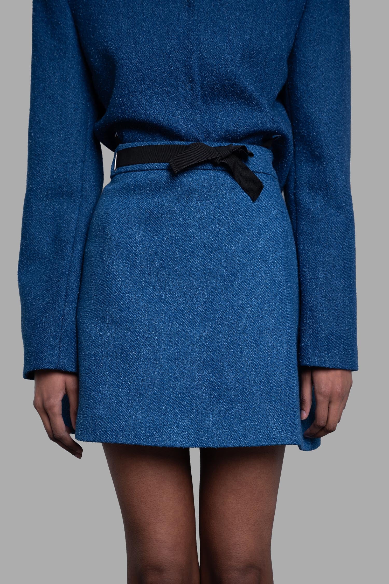 MSGM A-line Mini Skirt, front view on-model in blue textured fabric with black waist tie detail.