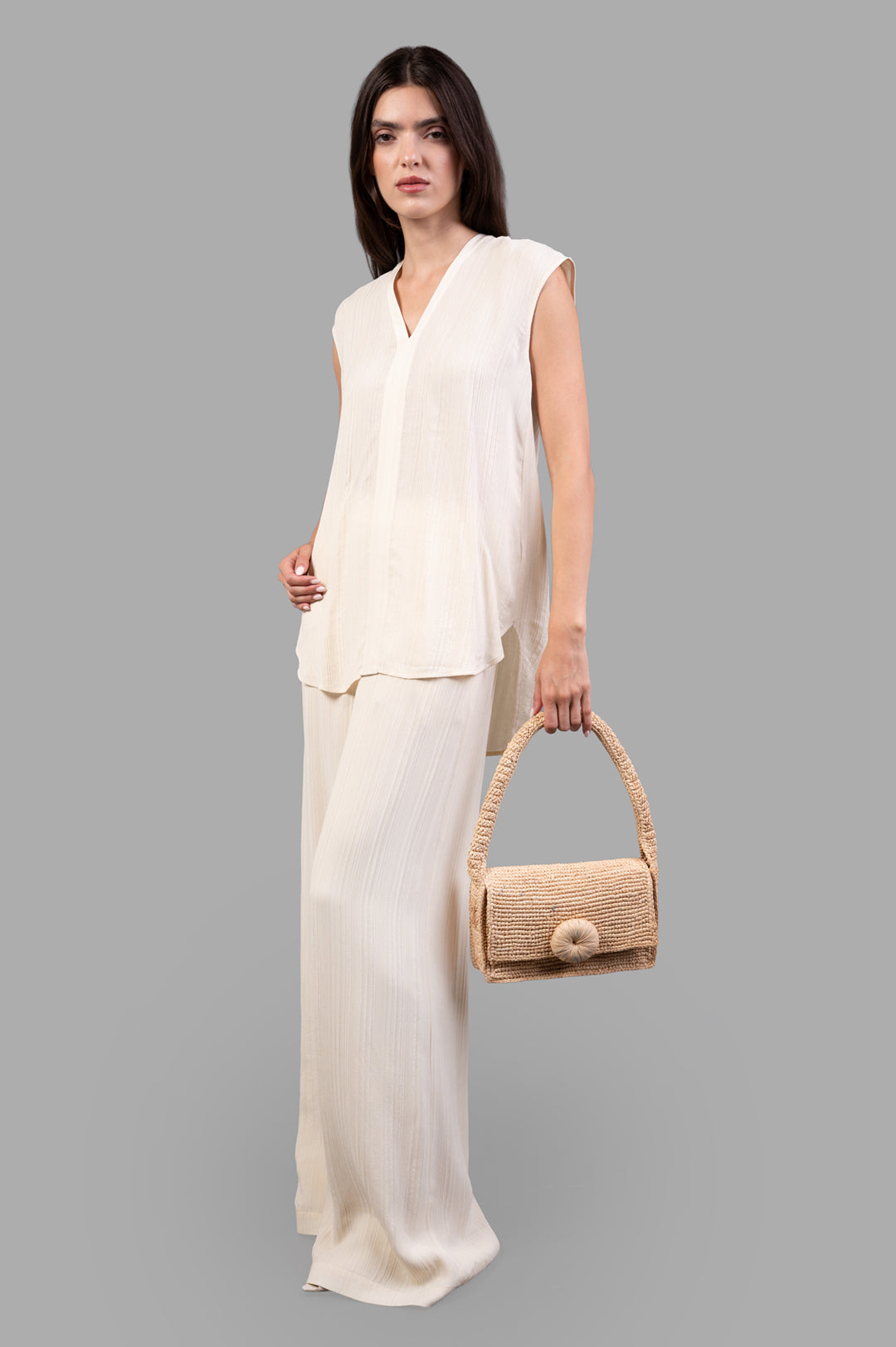 Joseph Lucien Pleat Jacquard Blouse in front view, sleeveless, with linear texture, worn with matching pants, straw bag in.
