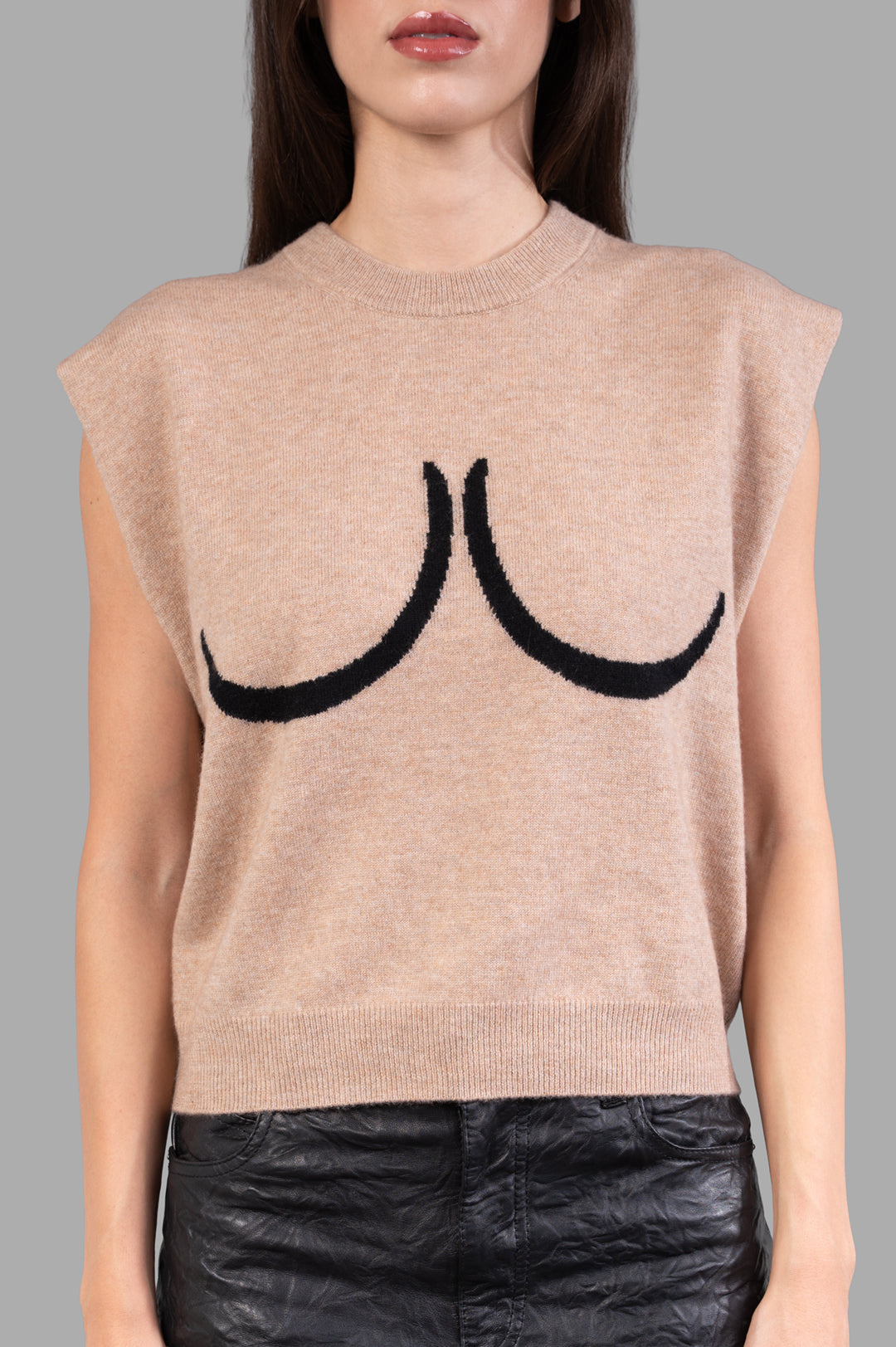 **Alt Text:** Natasha Zinko Breast Sweater Vest shown on model, featuring bold black breast motif and soft beige fabric.