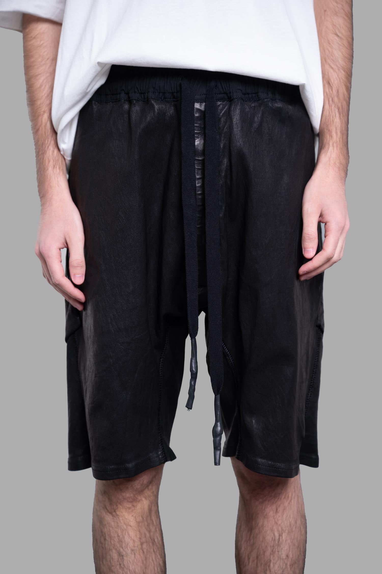 Isaac Sellam leather shorts feature a drawstring waist and side pockets, showcased in a close-up on a model's lower half.