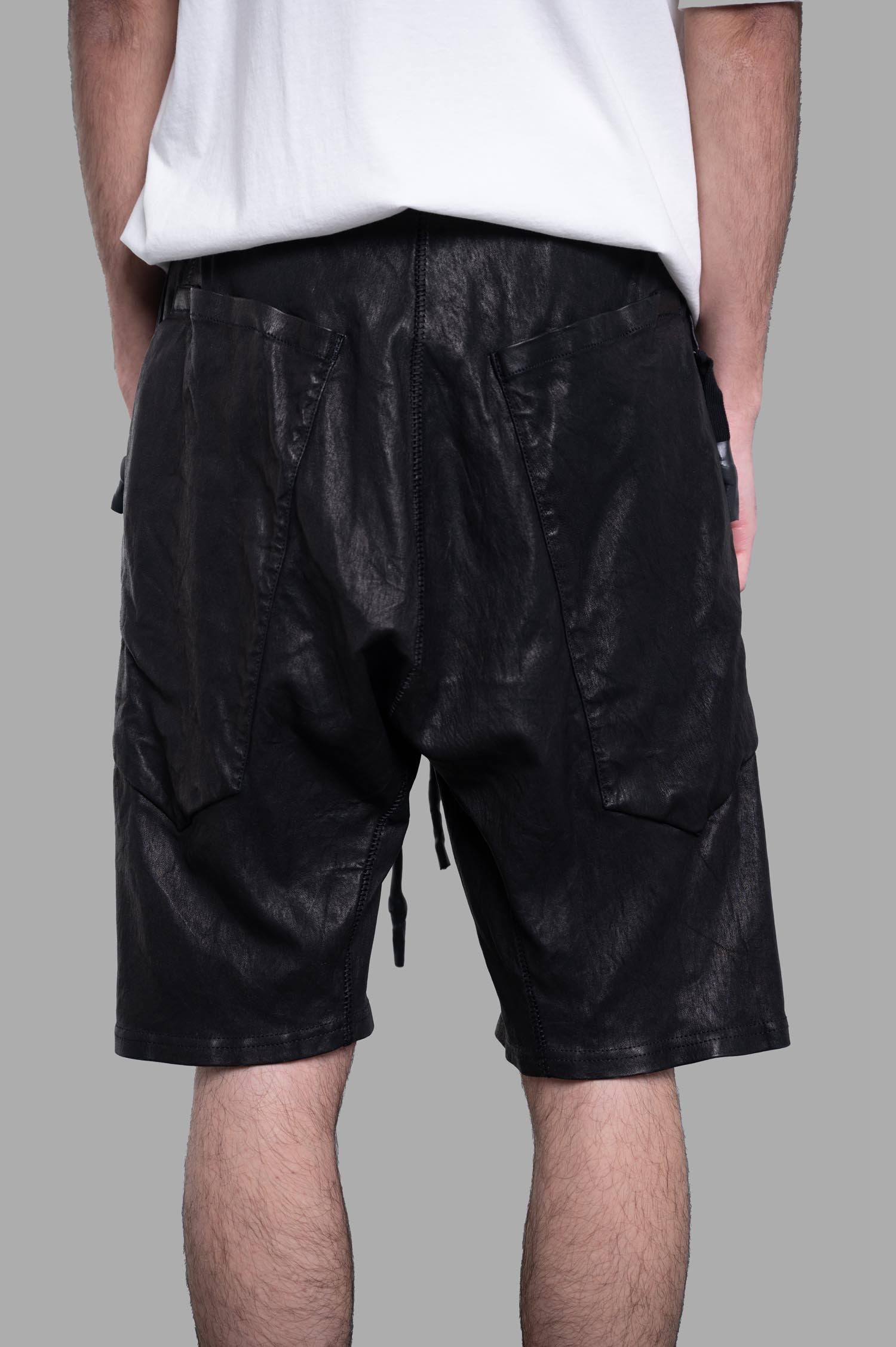 Isaac Sellam Leather Shorts showcasing a black leather design with a drawstring waist and back pockets on model's rear view.