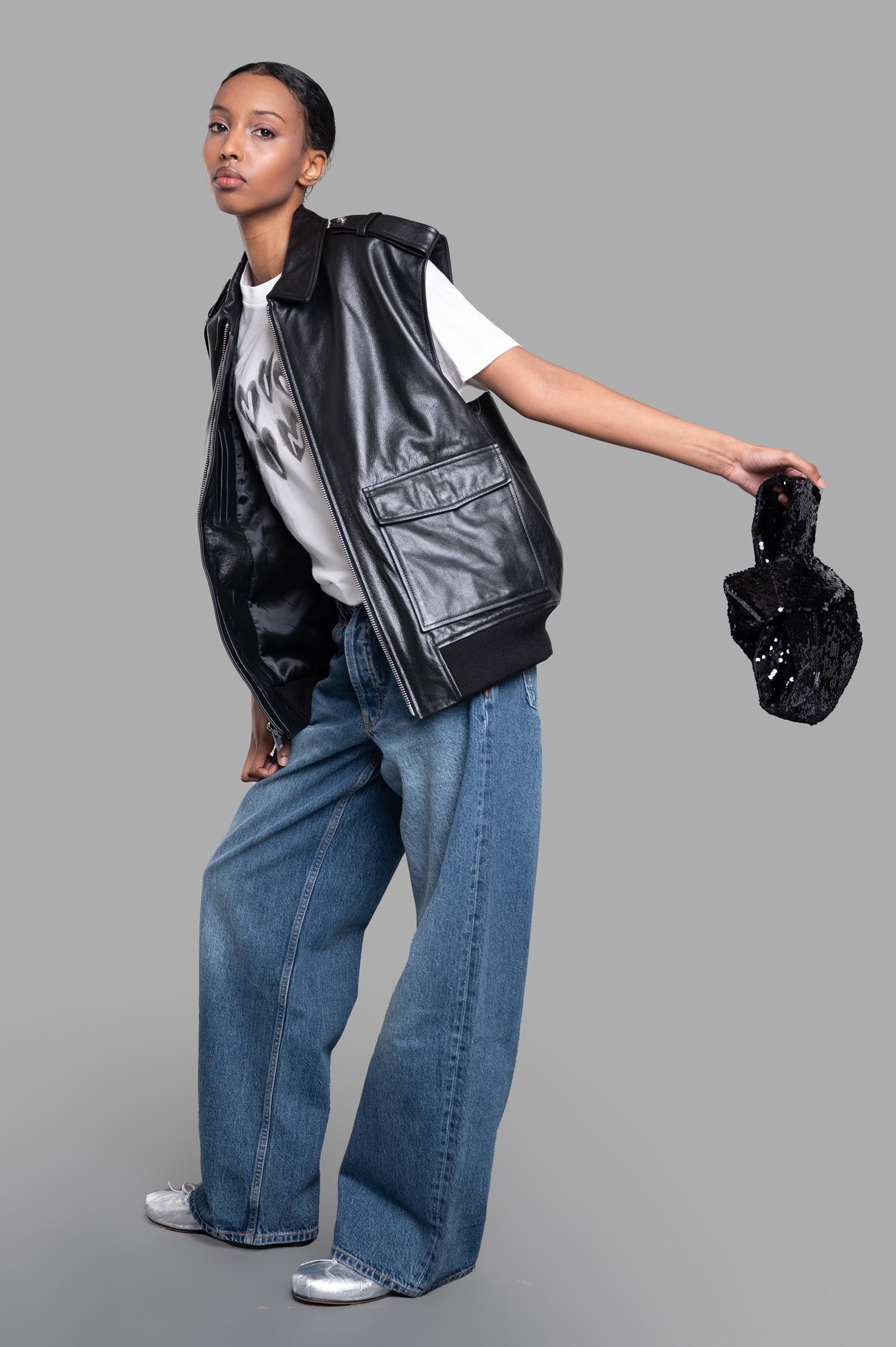 Anine Bing Sonnie Vest in black leather, modeled, featuring large patch pockets and ribbed hem, paired with jeans.