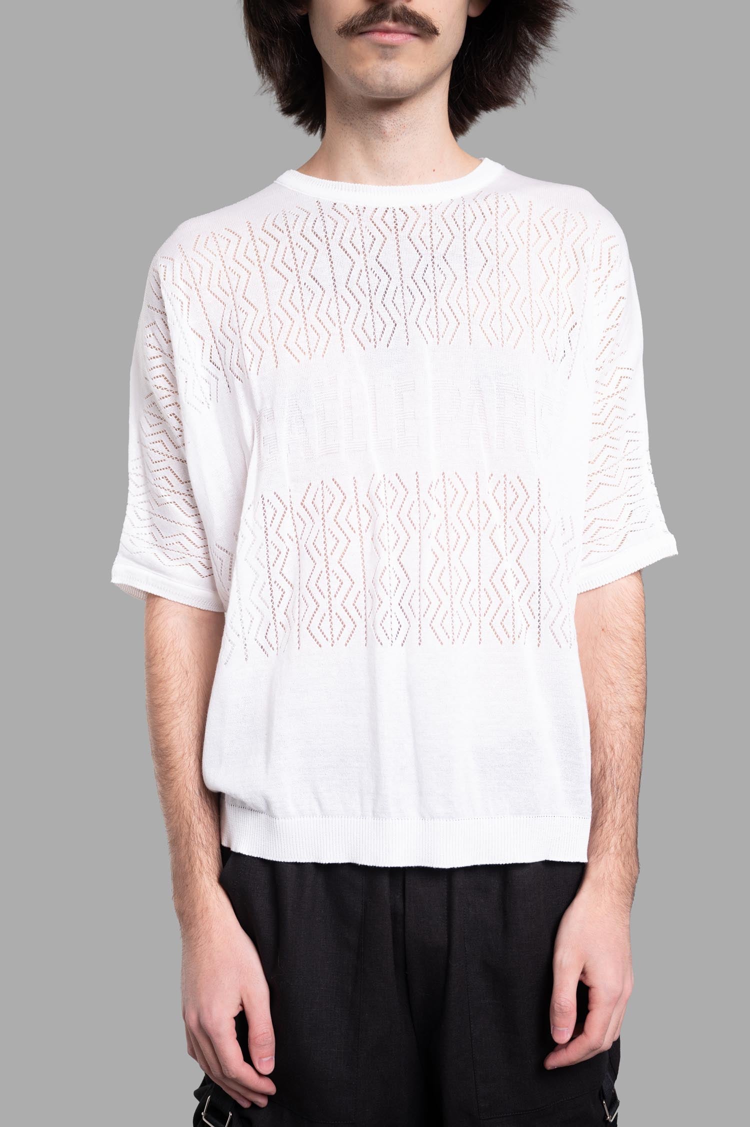 Gaëlle Paris. Knit Logo T-shirt in white, featuring a round neckline and intricate knit detail, modeled on a man.