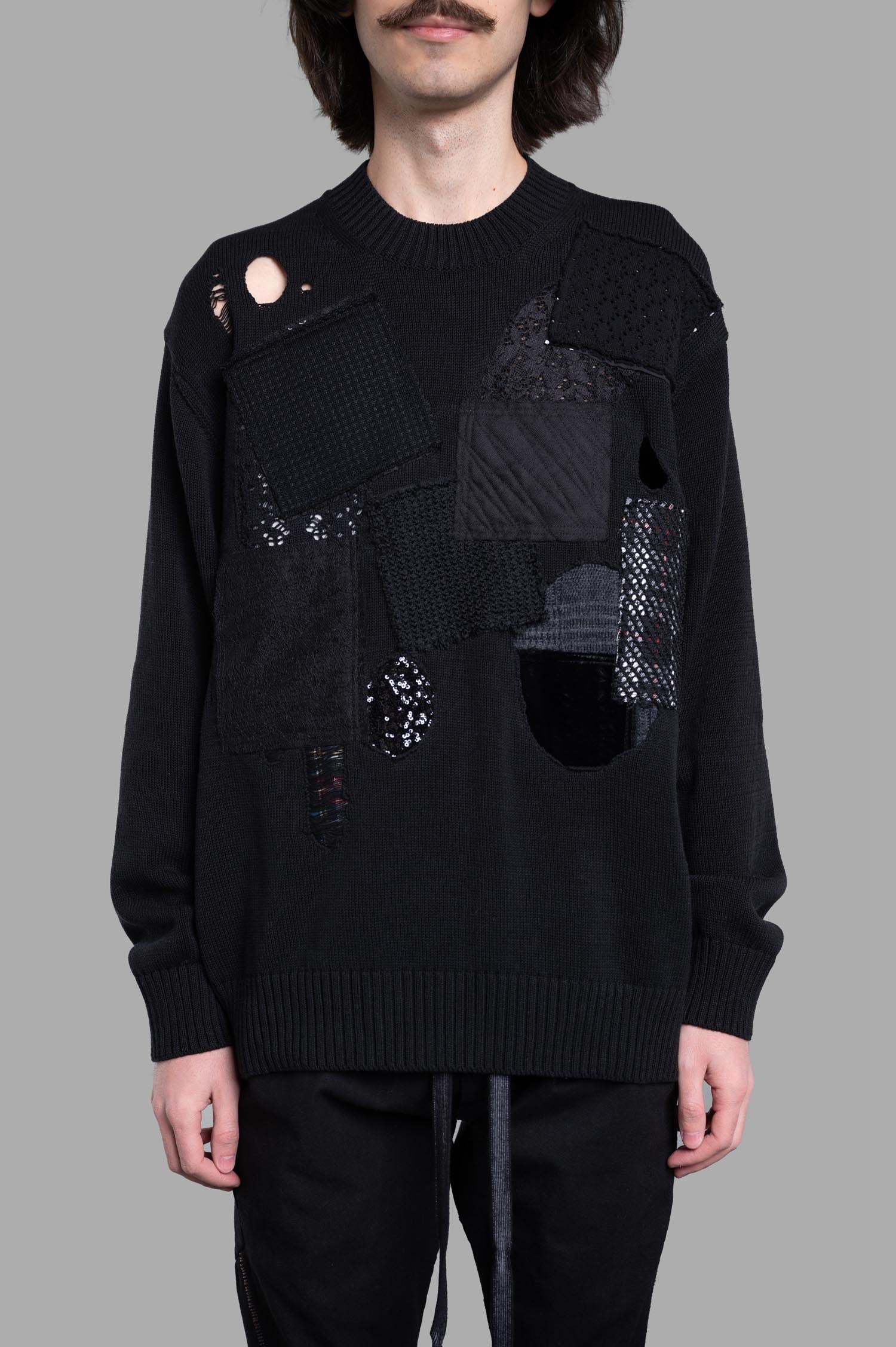 Junya Watanabe Patchwork Sweater features a unique front design with textured patches and distressed details in black cotton.