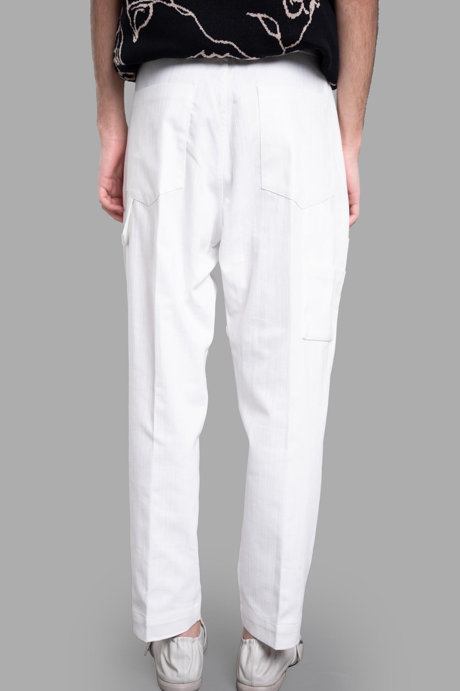 Gaëlle Paris. Straight-leg pants in white, showcasing a flattering back view with side pockets and subtle texture detail.