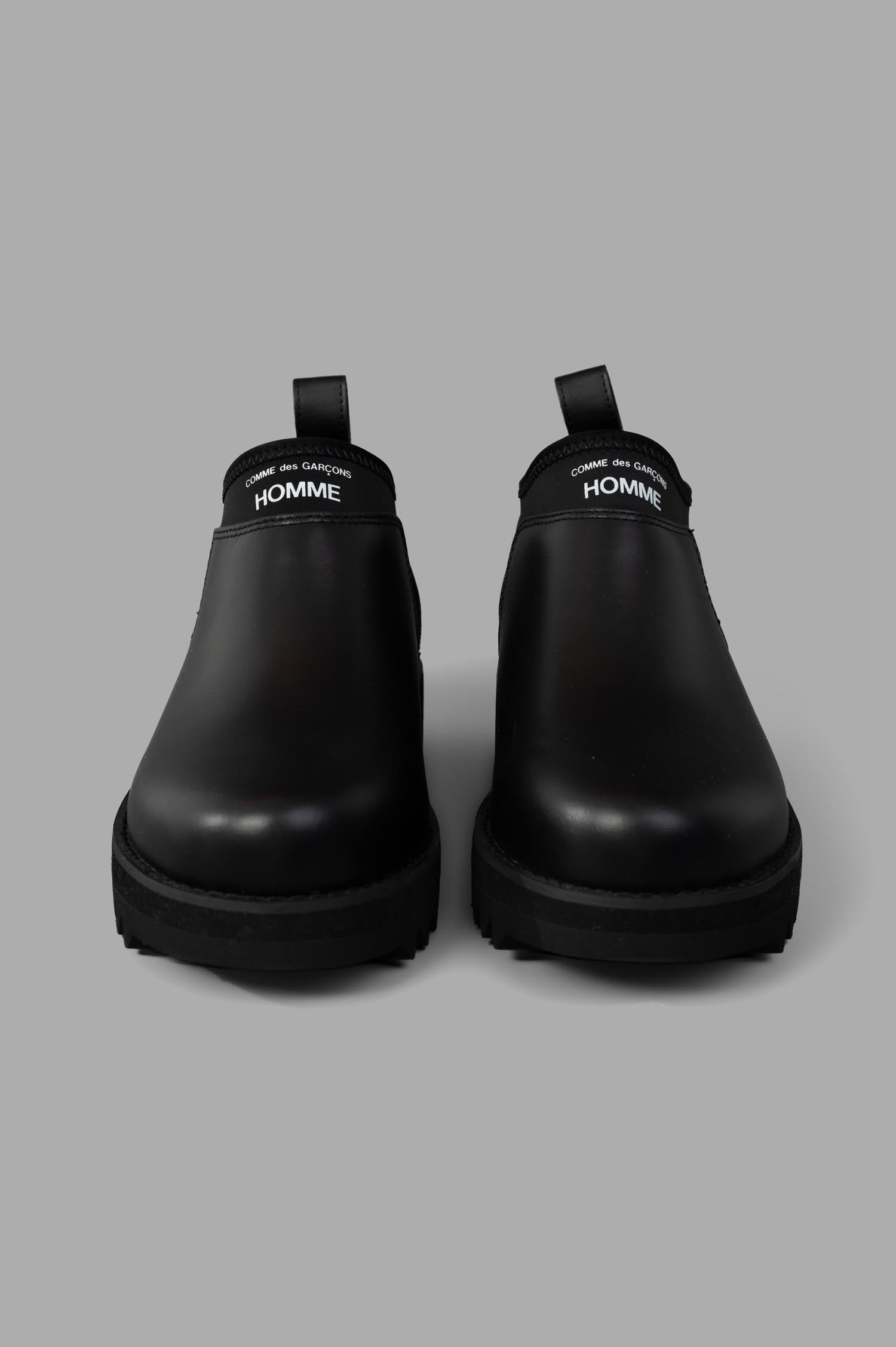 Comme des Garçons Logo Leather Boots in black, featuring a round toe and sturdy rubber sole, front view showing sleek design.
