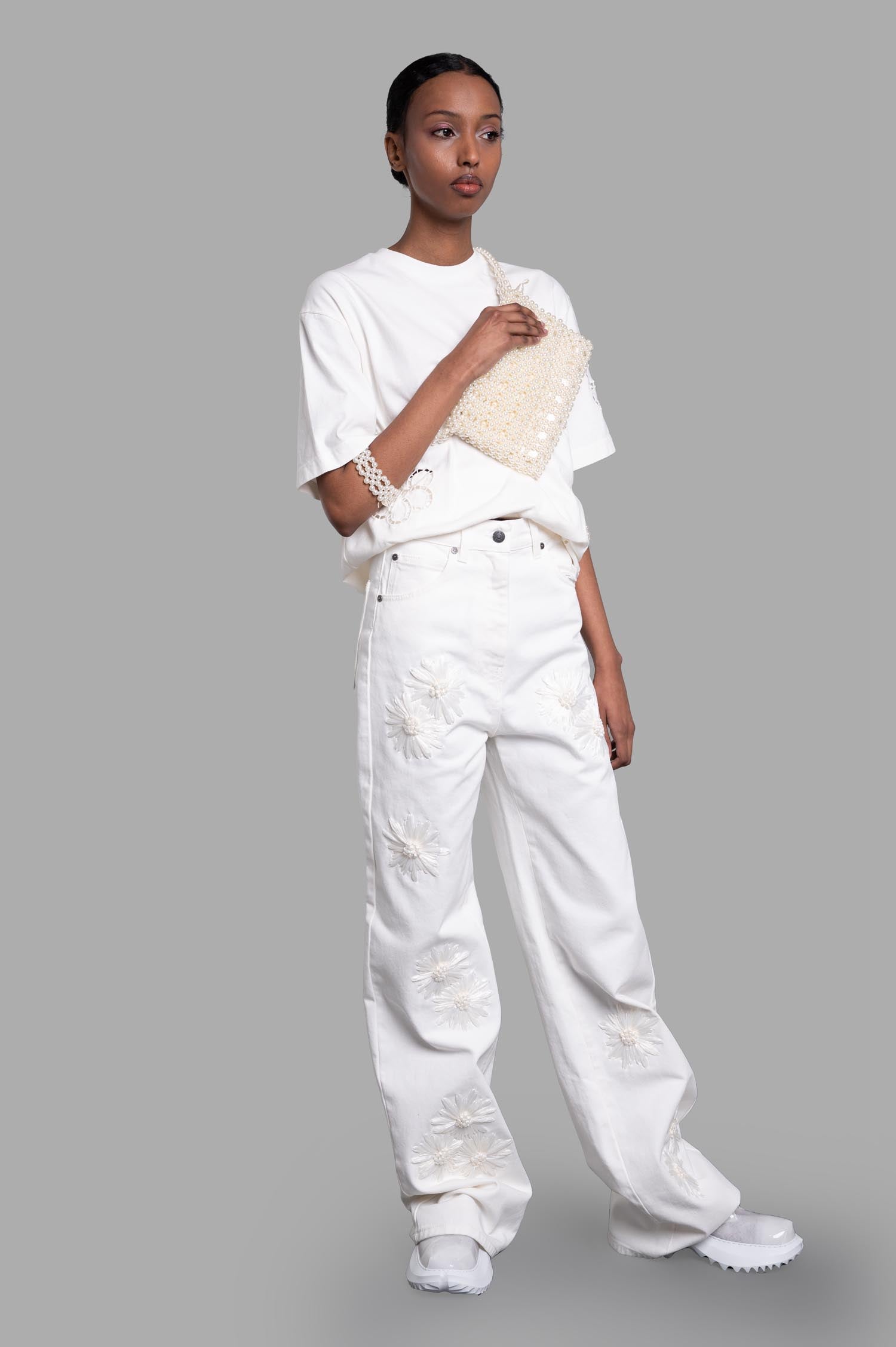 MSGM Denim Trousers with Raffia Flowers, white, front view on model, featuring belt loops and five-pocket design.