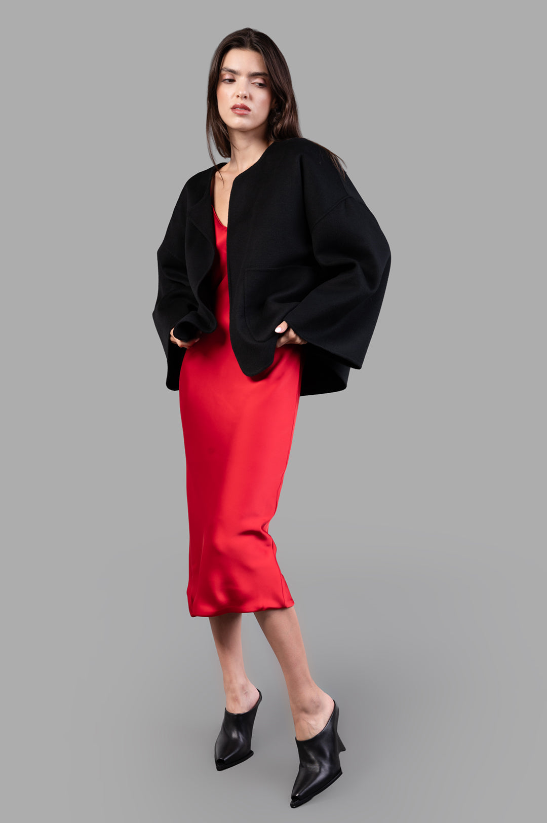 By Malene Birger Jacquie Wool Jacket in black, front view on model, featuring large pockets, over red dress.