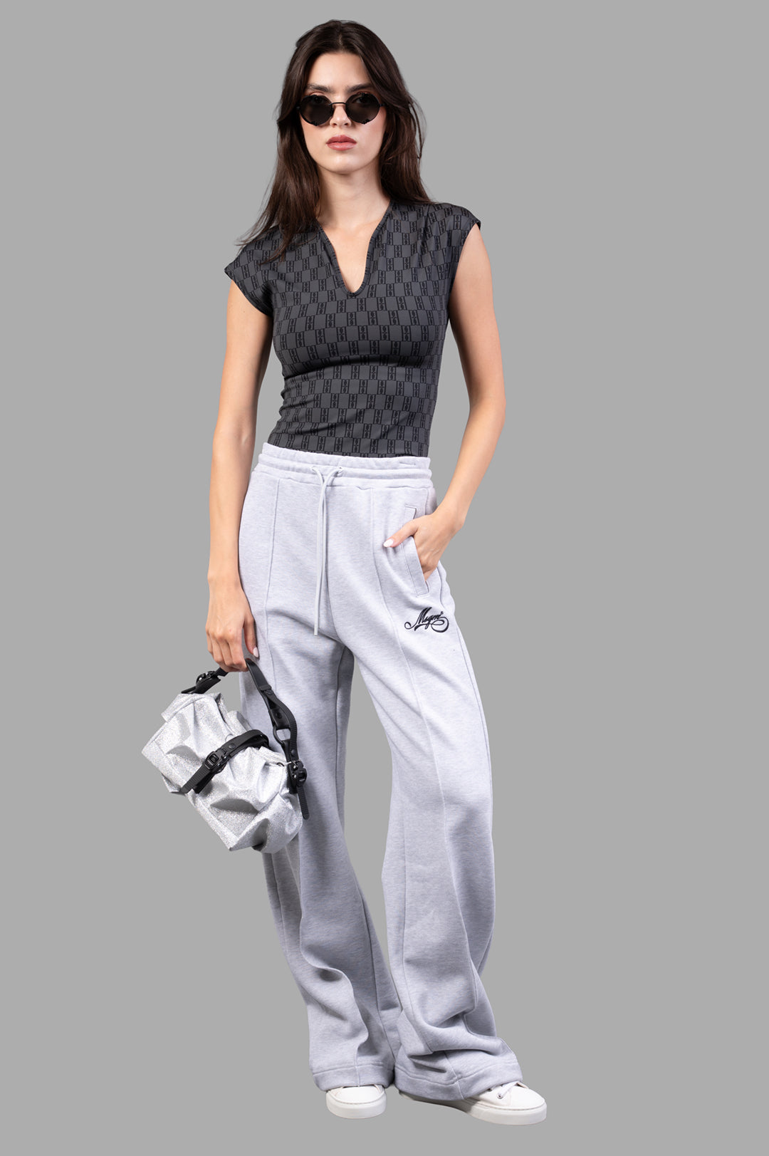By Malene Birger Venazia Athletic Top in black and grey, front view, V-neck, worn with grey pants and a handbag.