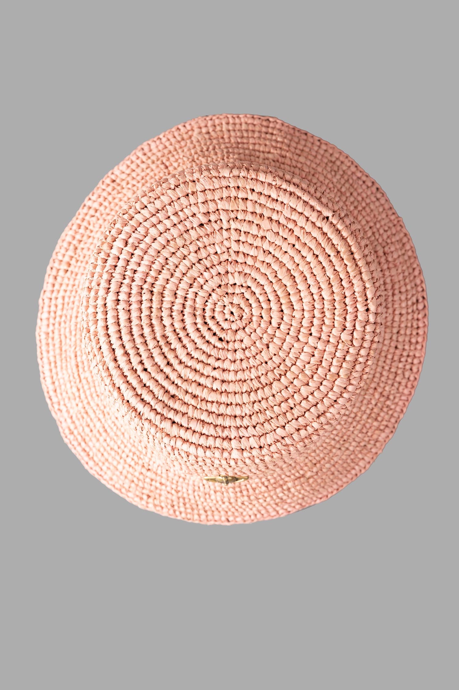 Vivienne Westwood Orb Raffia Bucket Hat seen from above, showcasing its circular woven structure and soft pink color.