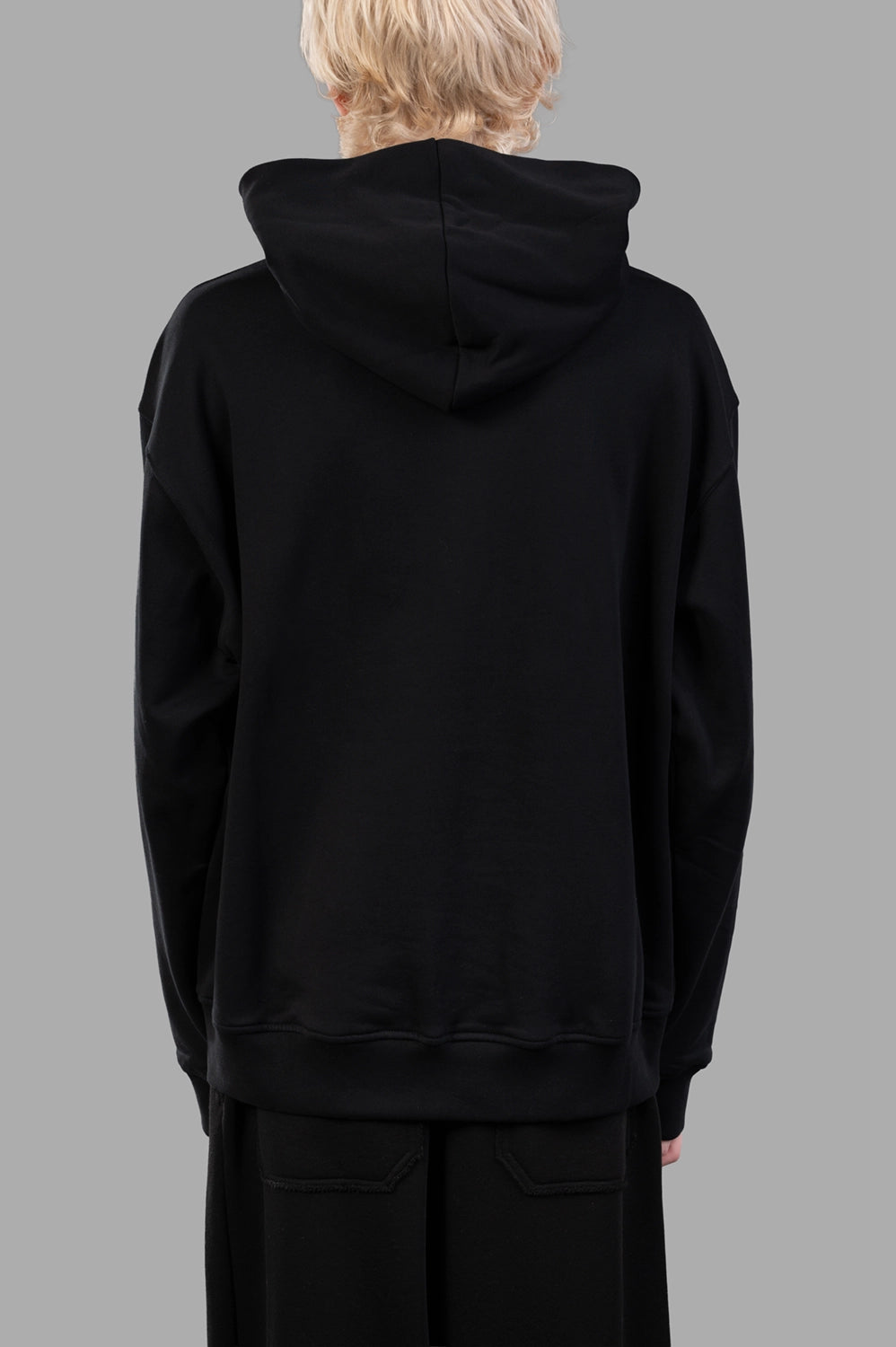 Front close-up of black hoodie showing tonal embossed logo and kangaroo pocket