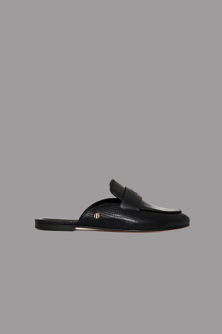 Anine Bing Corrine Mules in black leather, side view showing faux lizard texture and gold-tone monogram detail.
