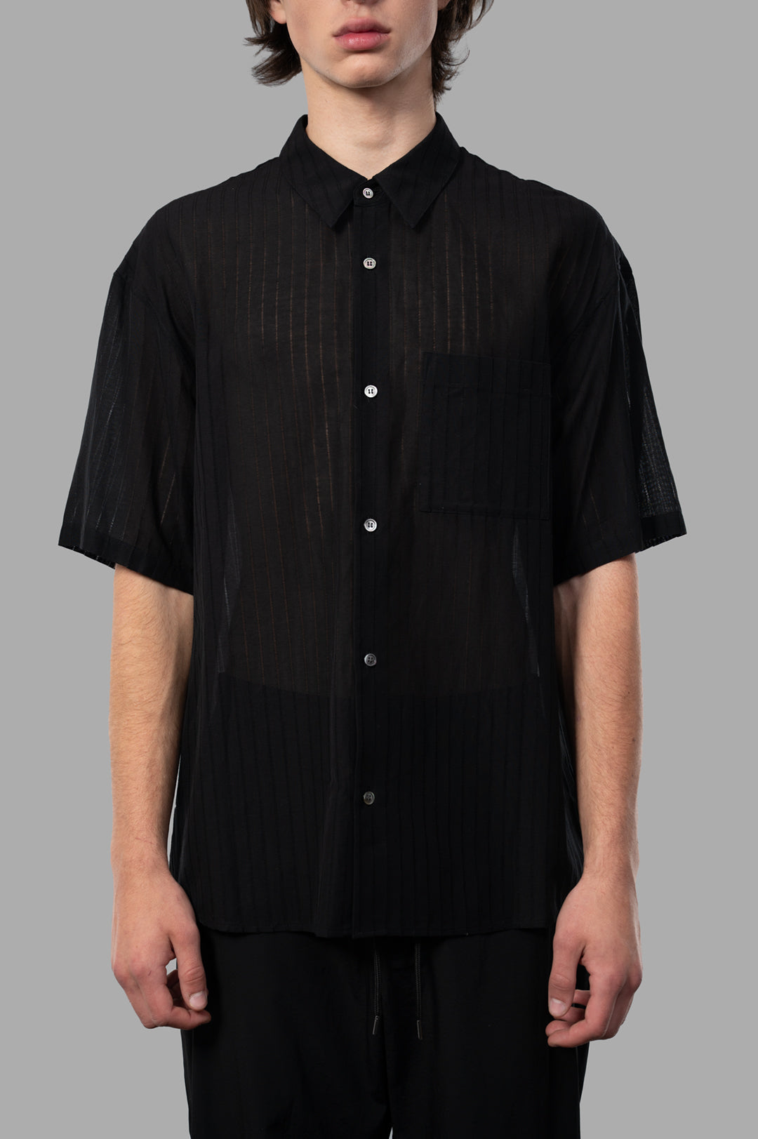 Attachment Textured Resort Shirt in black, showcasing a sleek short-sleeve design and vertical striped texture on model.