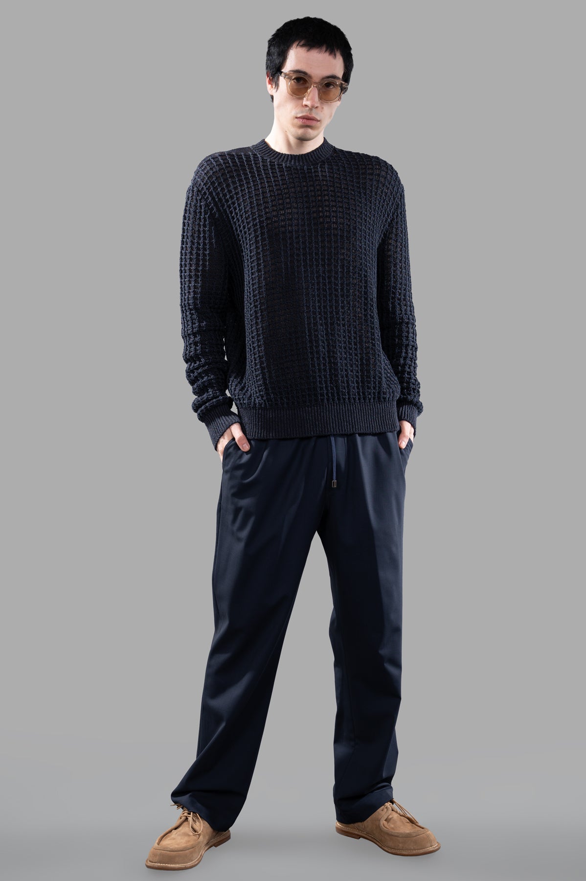 AION Cable-knit Sweater on-model, front view; styled with navy pants and brown shoes, showcasing textured knit design.