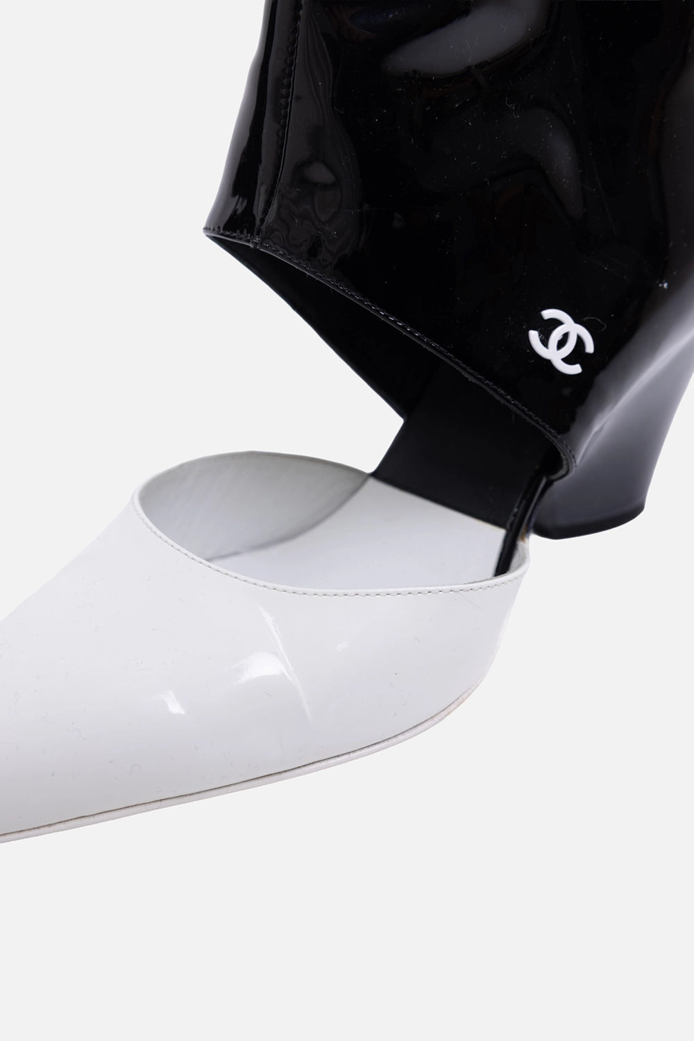Pre-owned Chanel ankle boots in black and white, close-up view, white CC logo on glossy black ankle